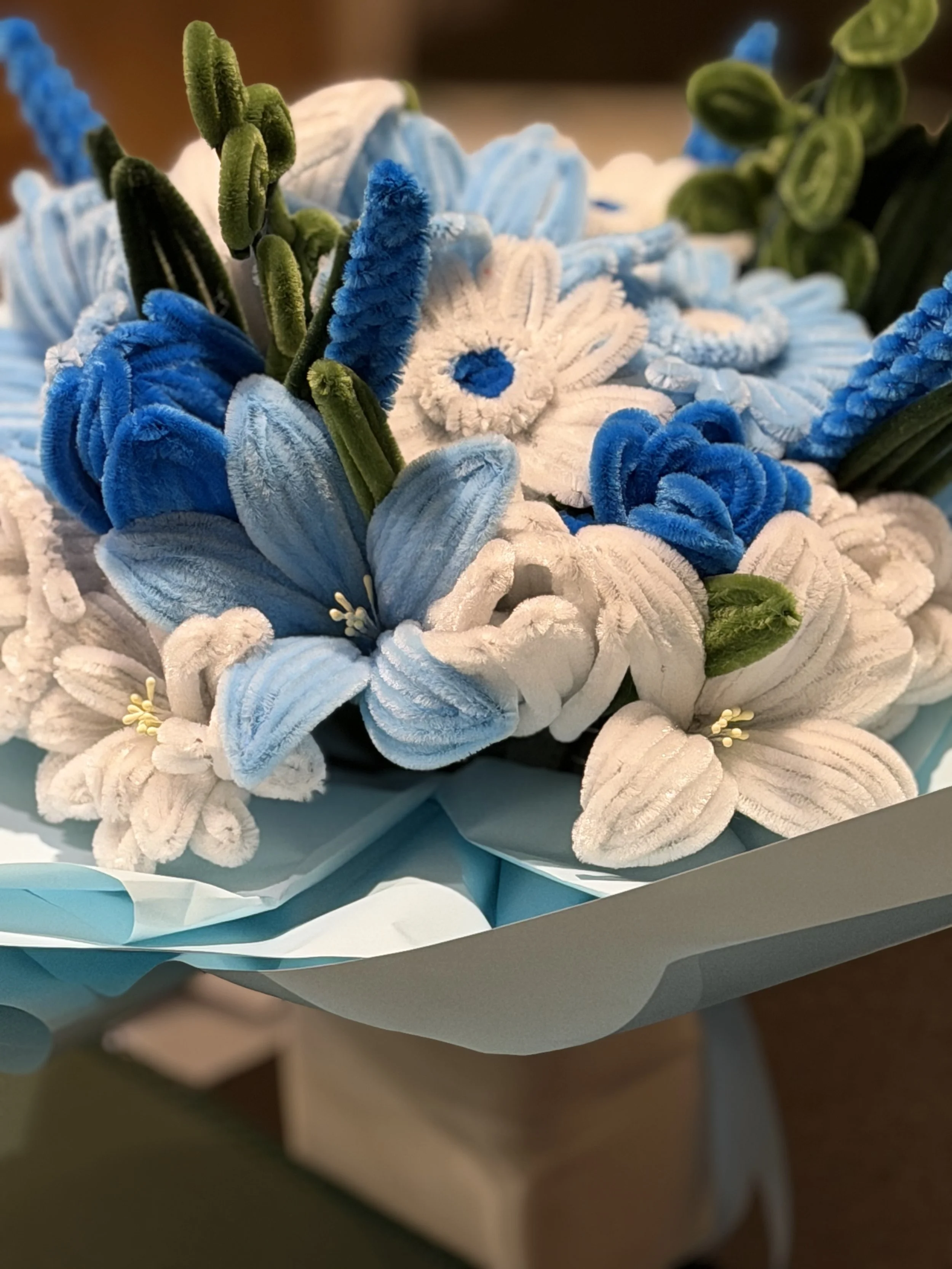 Close-up of plush fabric flowers in white, blue, and green, arranged in a decorative bouquet.