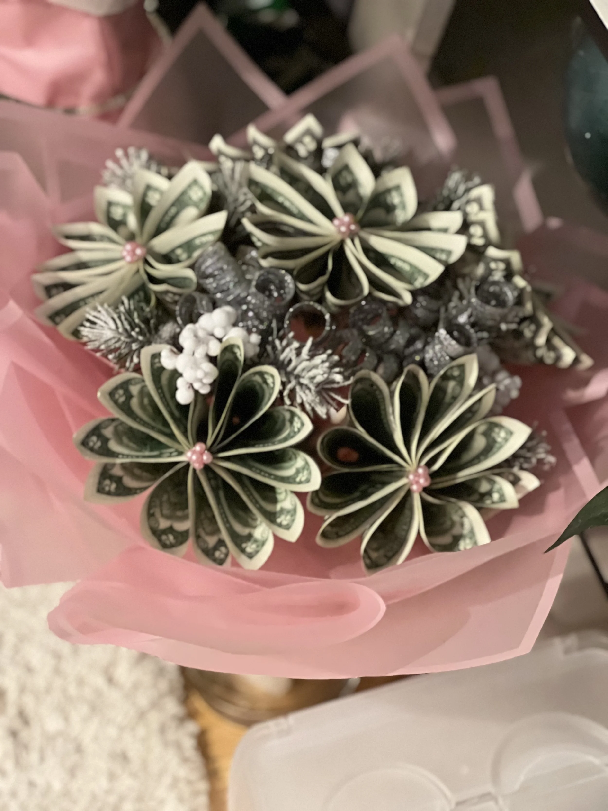 A bouquet of decorative paper flowers with pink beads at the center, wrapped in pink paper.