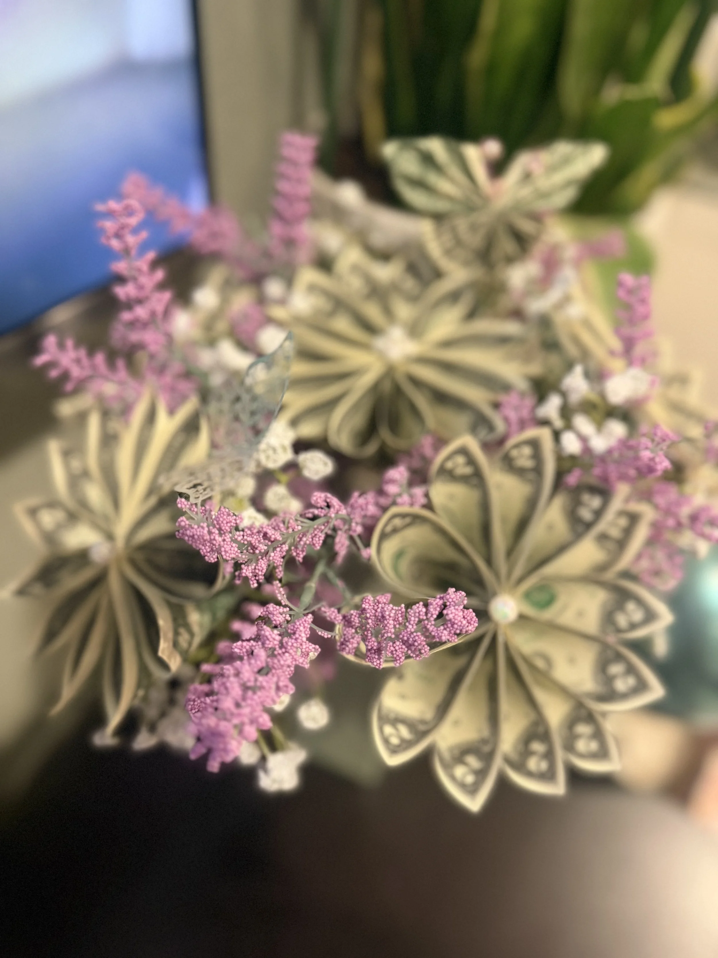 Close-up of a decorative plant with pink and white flowers, green leaves, and butterfly-shaped ornaments.