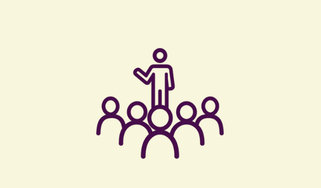A person standing on a platform speaking to a group of people.