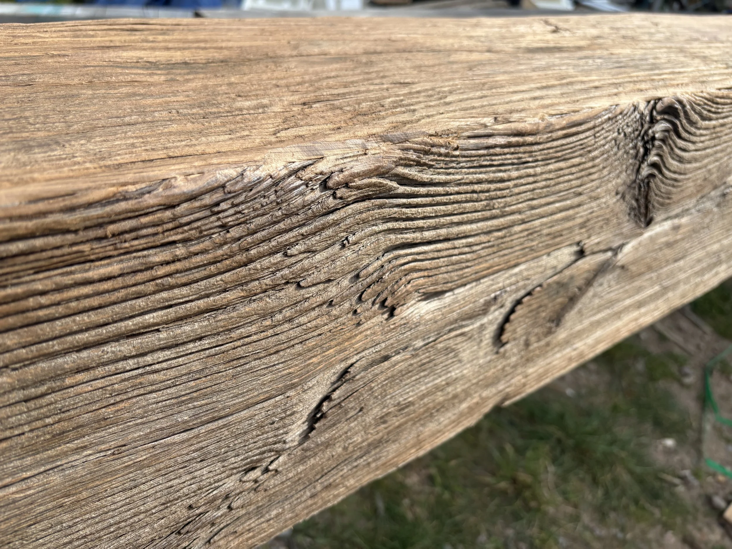 Close-up of reclaimed oak beam surface showing aged grain, weathered texture, cracks, knots and worn character. These natural details give antique oak box beams their depth and aged appearance.