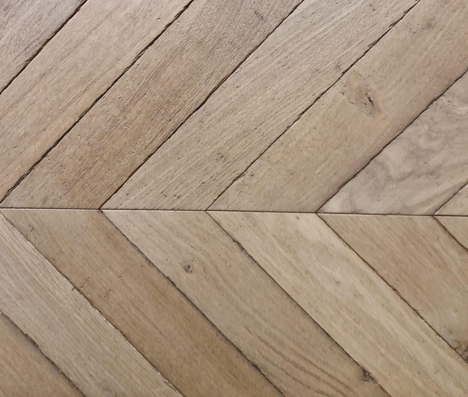 Reclaimed oak chevron parquet flooring with natural grain, subtle tonal variation and an aged timber finish.