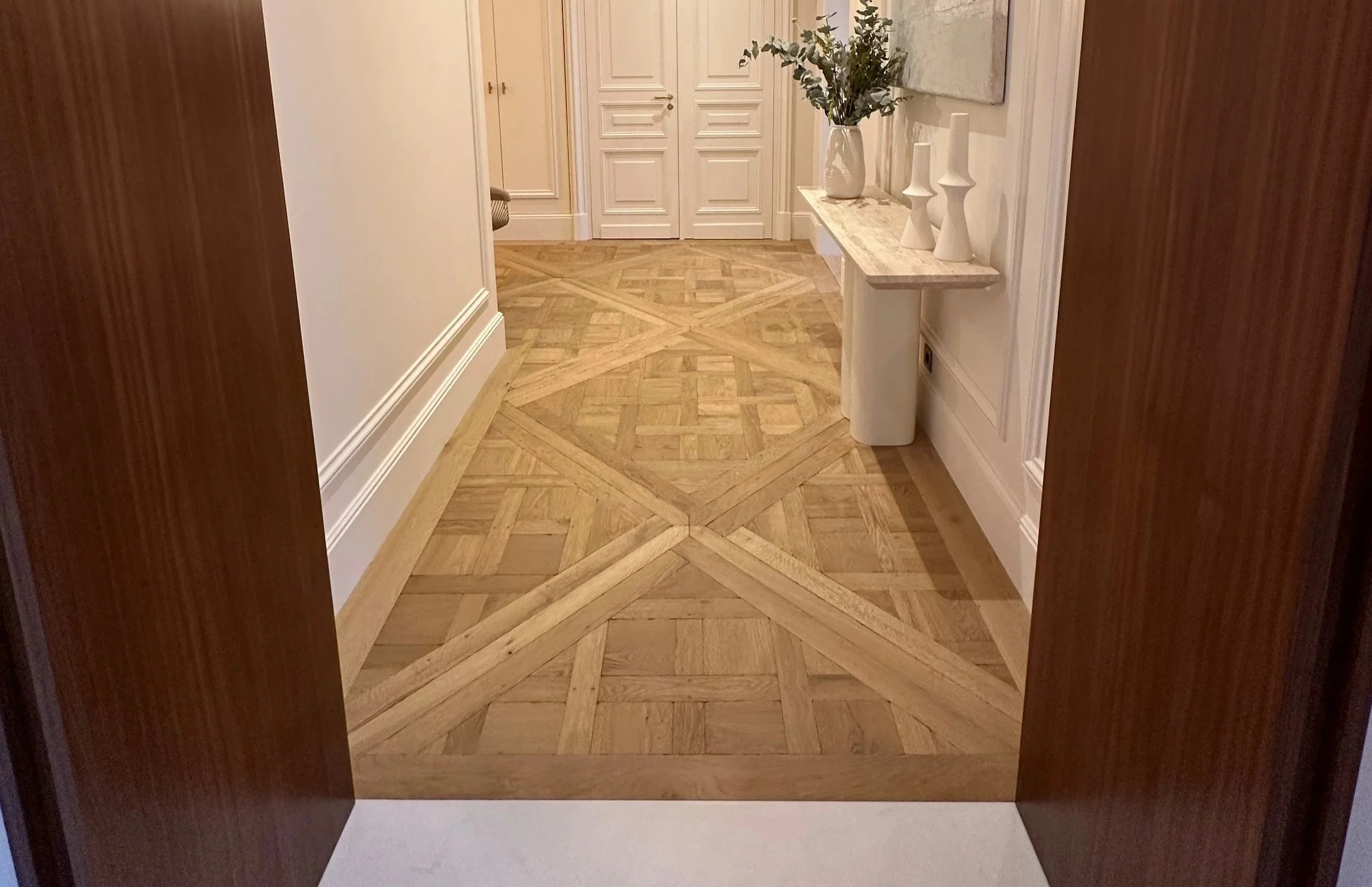 Light oak parquet flooring in a hallway, adding warmth, texture and timeless character to the interior.