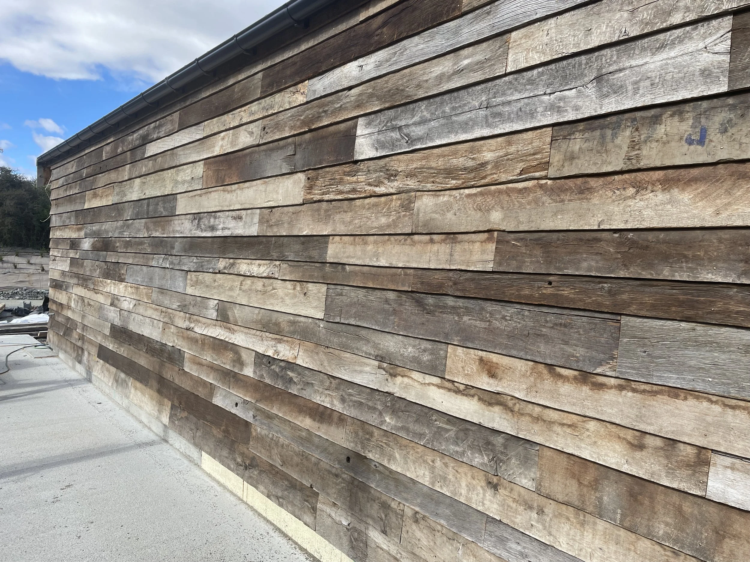 Reclaimed European oak boards used as exterior rainscreen cladding with natural weathering and tonal variation.