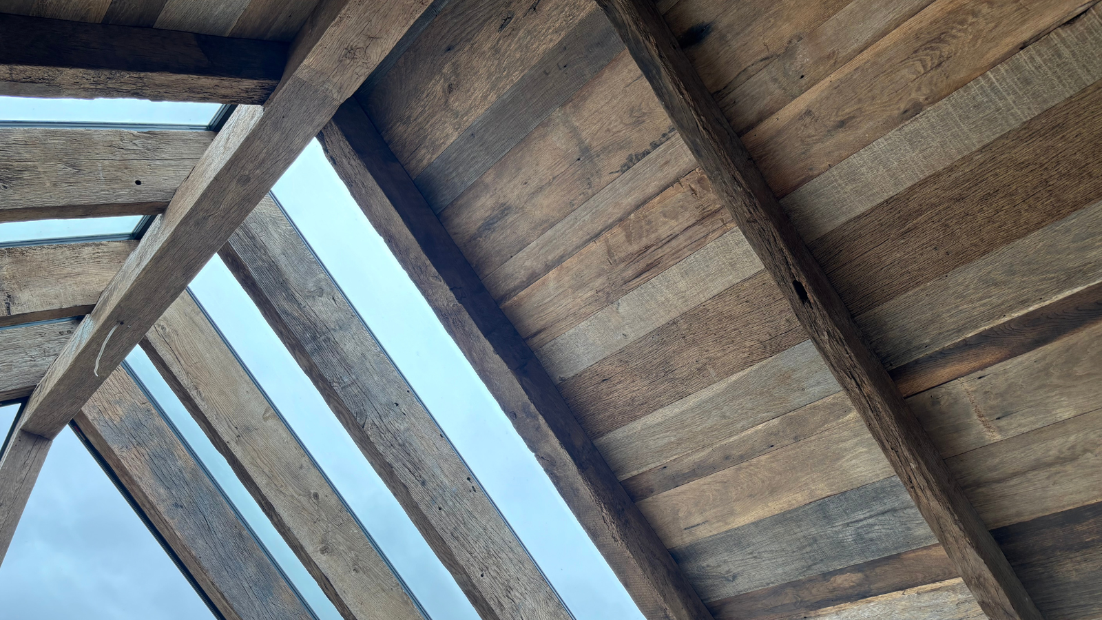 Reclaimed European oak ceiling lining with exposed beams, natural aged grain and tonal variation.