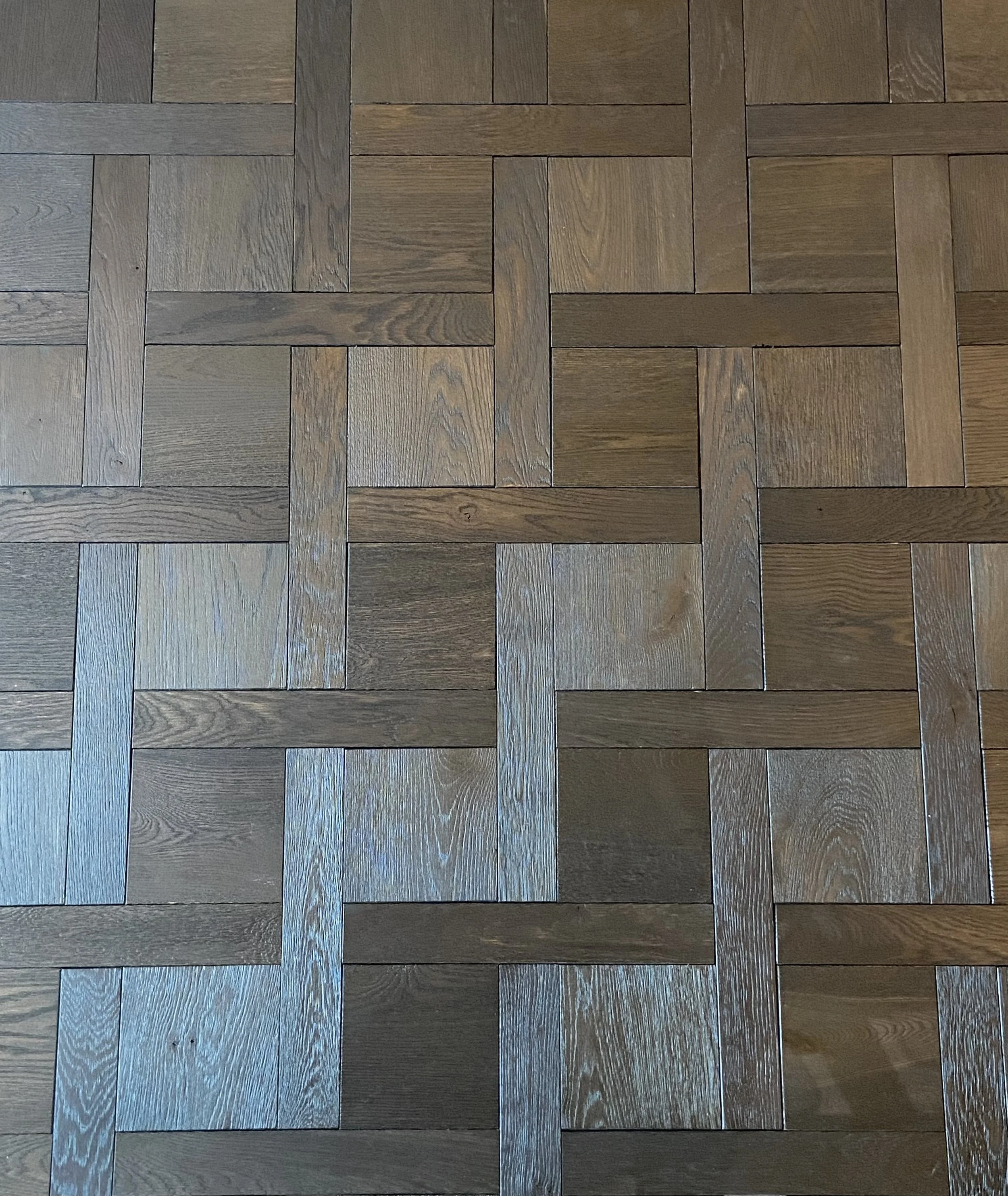 Close-up of dark reclaimed oak parquet flooring showing textured grain, aged surface detail and natural tonal variation.