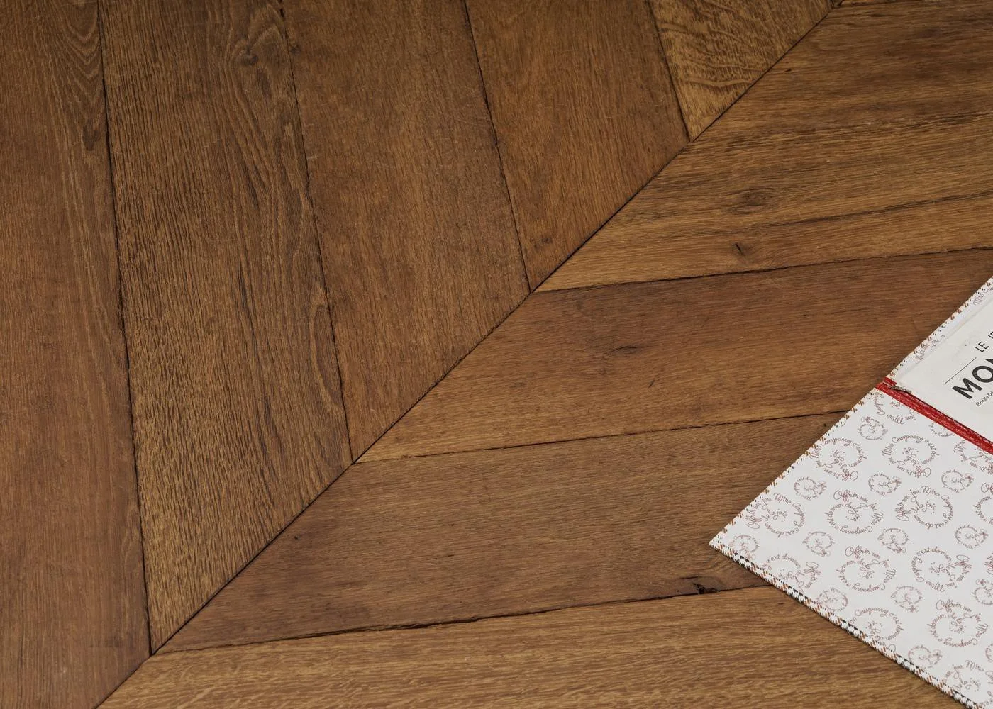 Close-up detail of aged oak flooring laid in a geometric pattern, showing rich colour variation and natural texture.