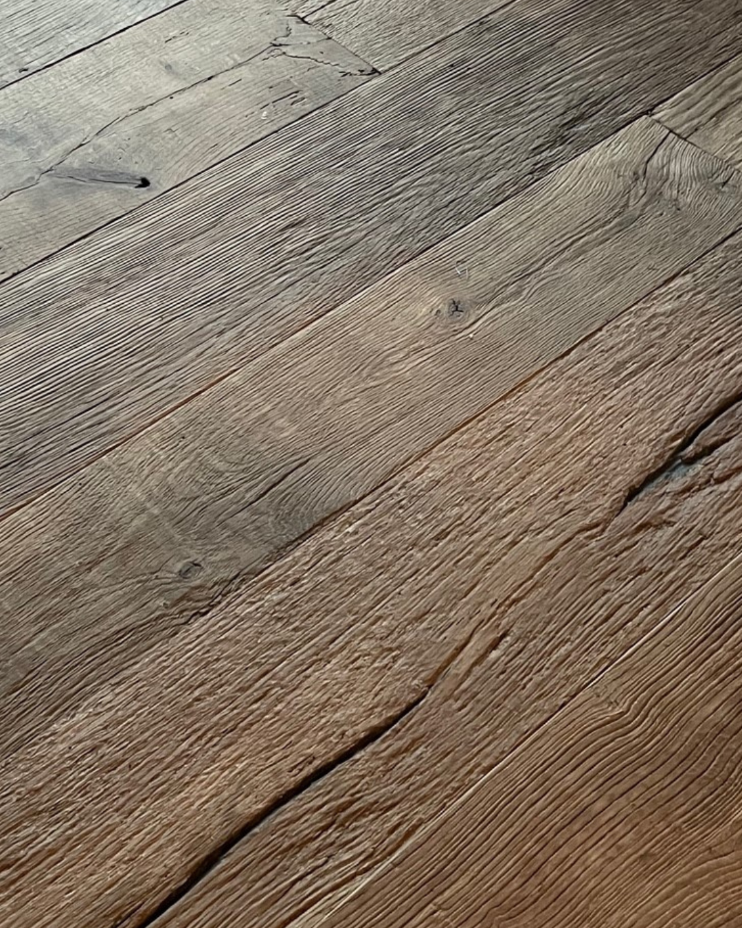 Close-up of aged wooden floorboards showing grain, knots, and cracks.