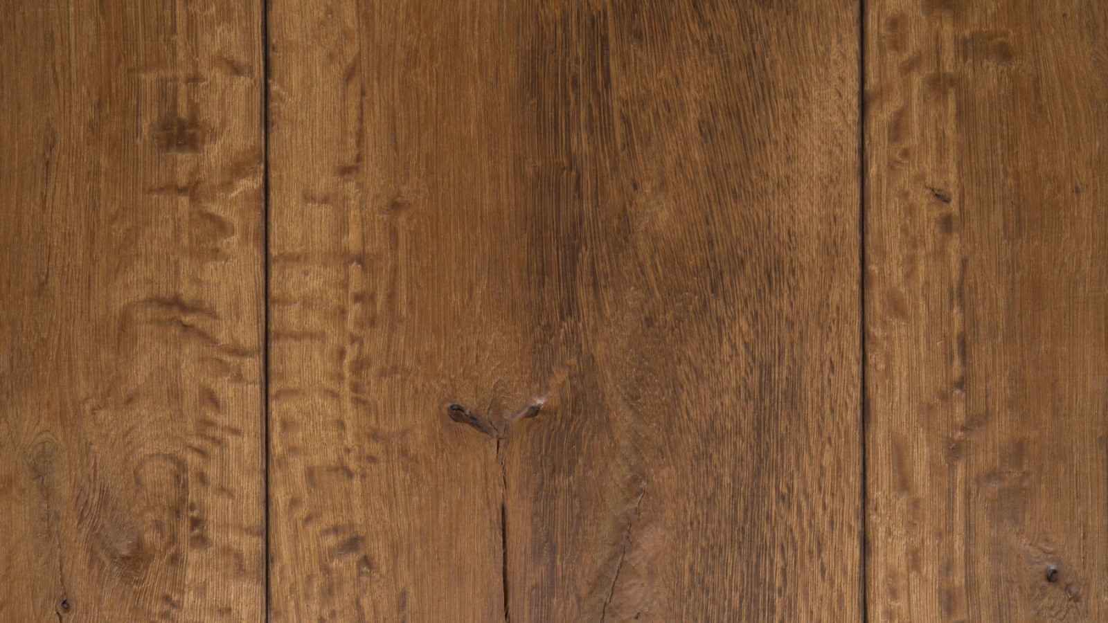 Close-up detail of vintage French oak flooring showing aged grain, warm brown tones and natural timber character.