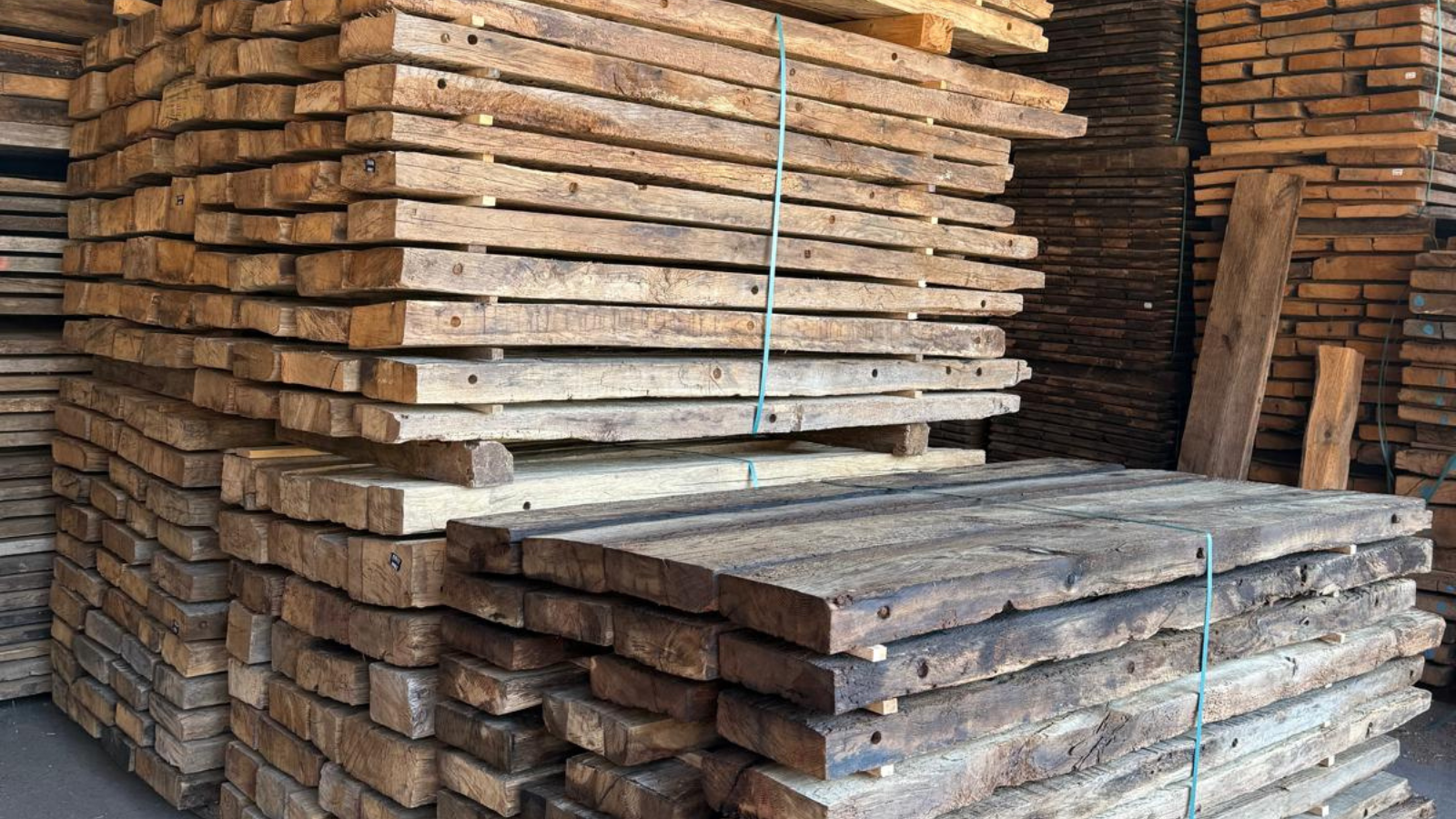 Stacks of reclaimed European oak timber showing aged surface character, natural grain and variation.