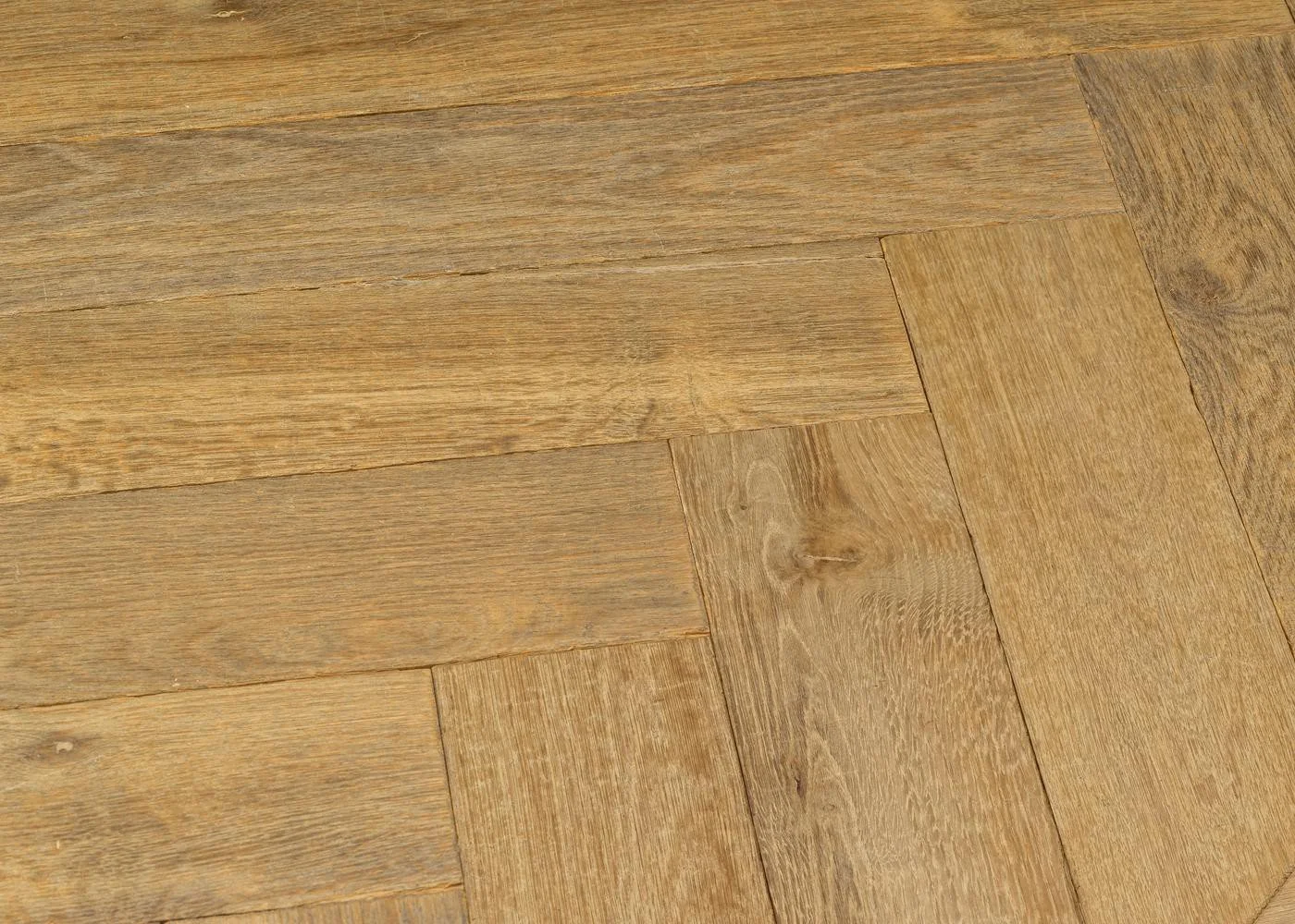 Close-up of warm oak parquet flooring with visible grain, saw marks and a naturally aged surface.