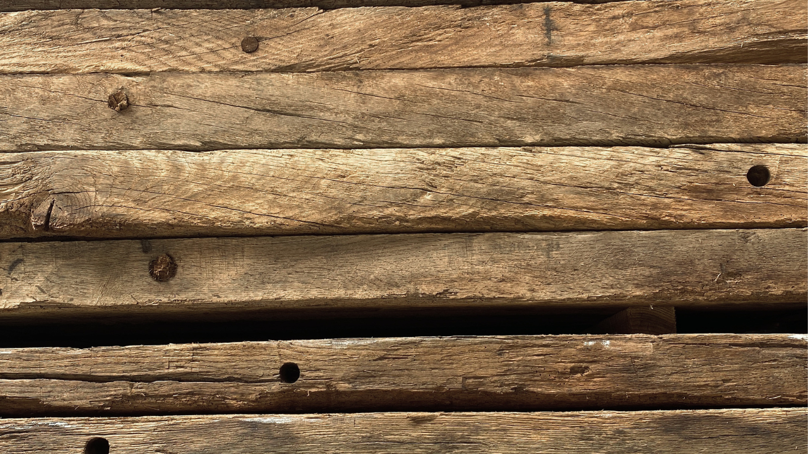 Reclaimed oak beams showing old peg holes and hand-hewn surface marks.