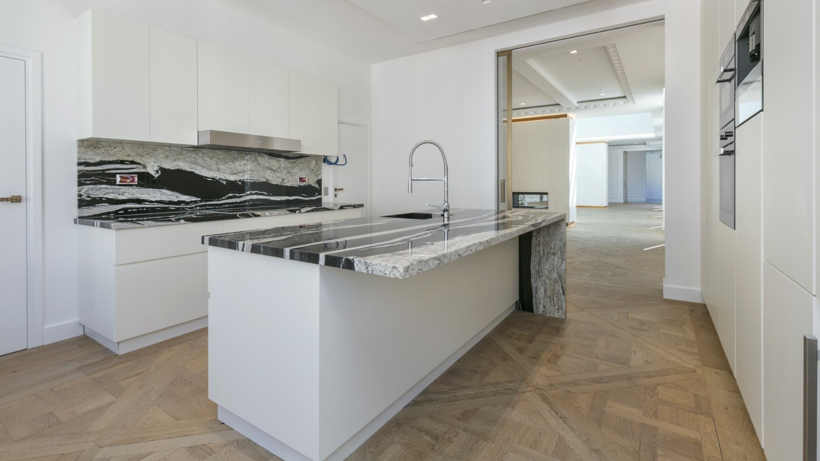 Reclaimed oak parquet flooring in a modern white kitchen with natural timber texture, aged character and herringbone pattern.