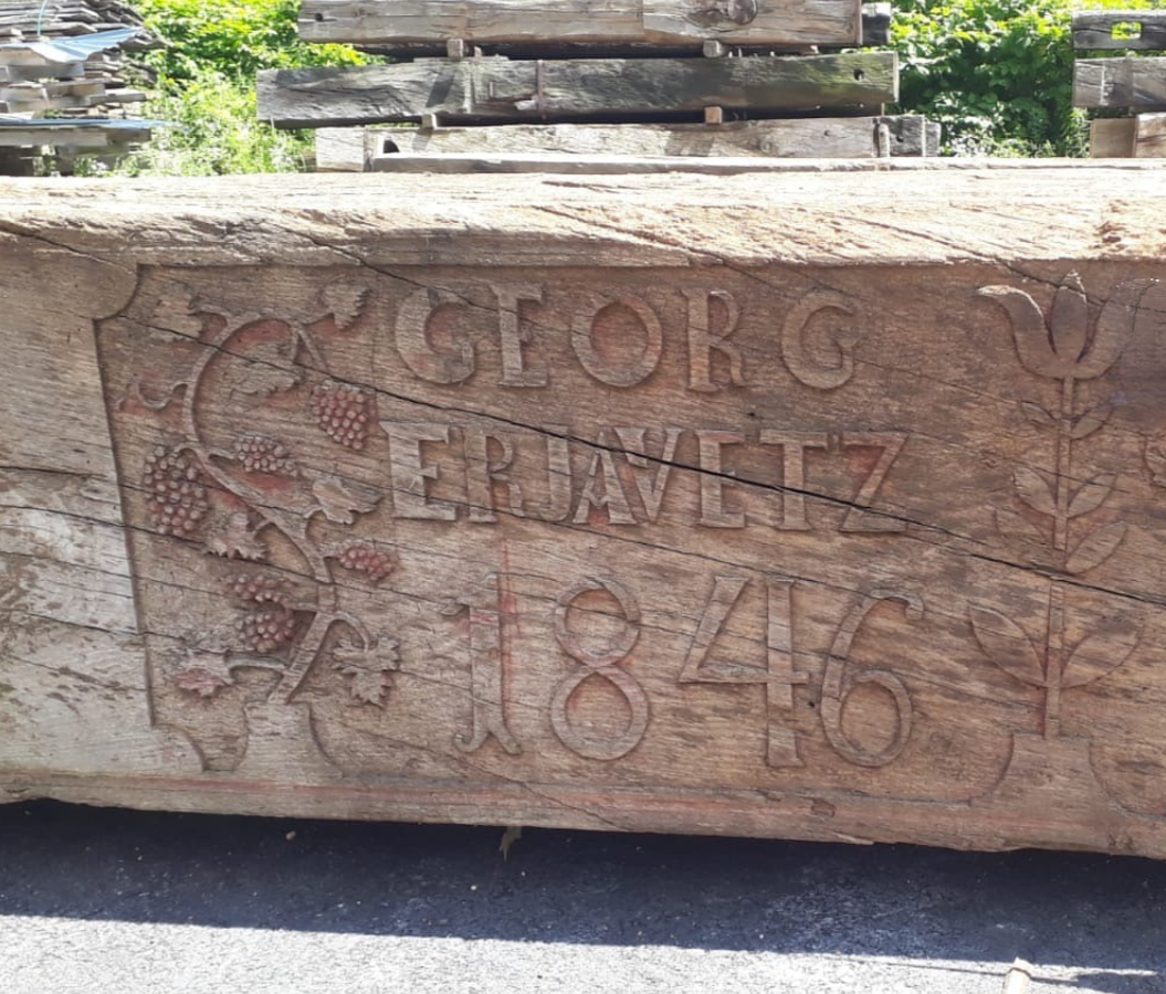 A wooden carved sign with the text 'George Jeravetz 1846' and decorative floral carvings.
