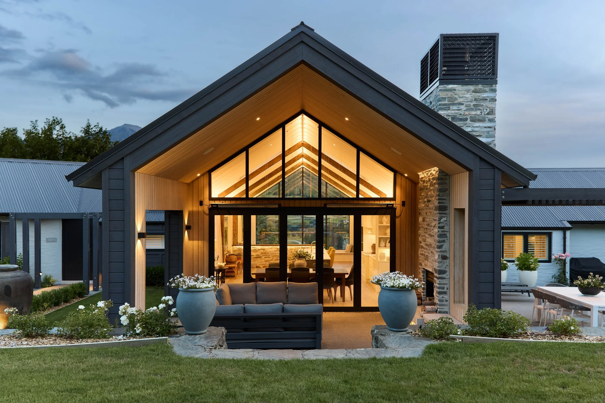 Modern house with wooden beams large windows, and a peaked roof, rustic modern.
