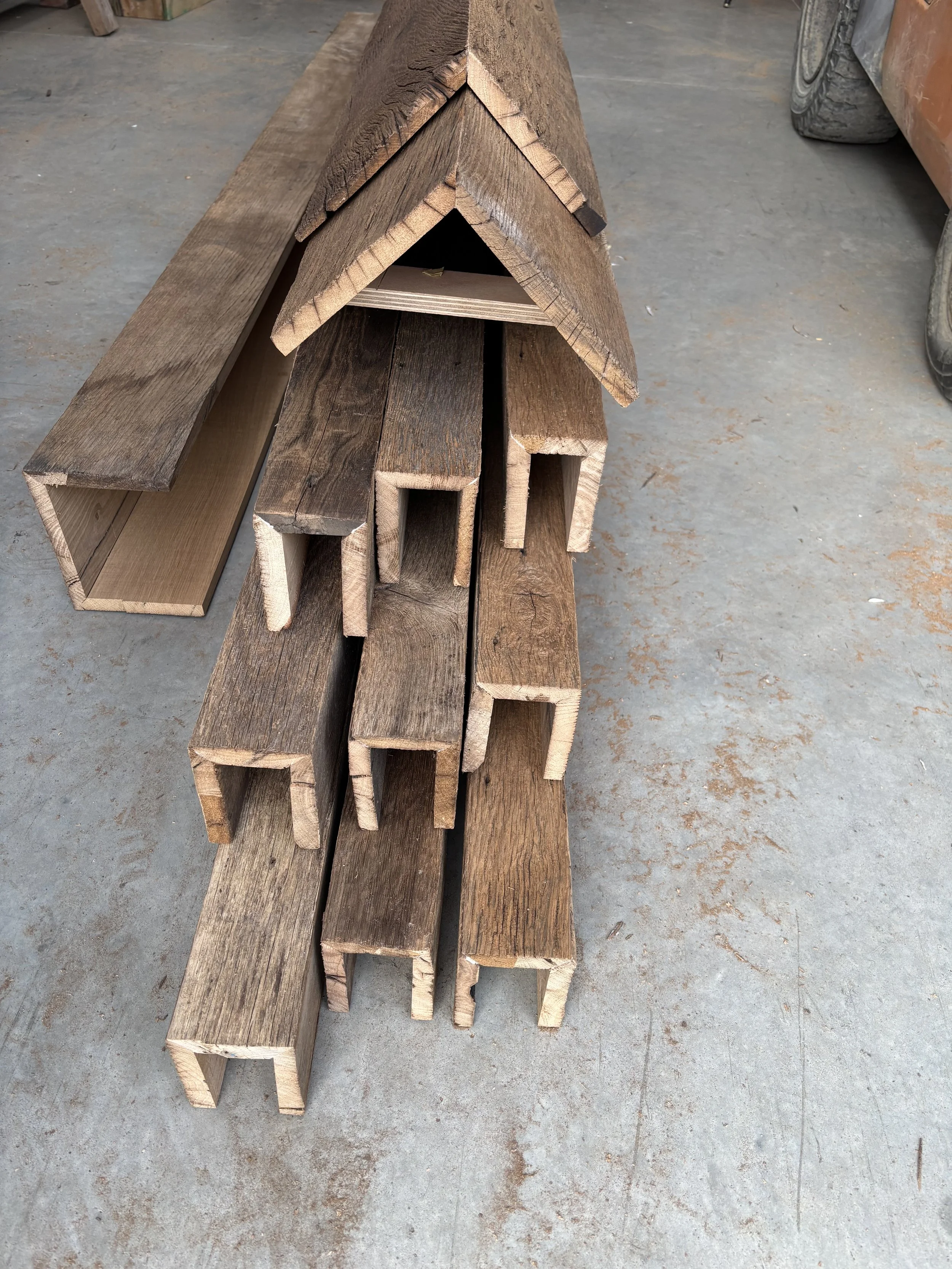 Reclaimed oak box beam sections showing the hollow construction used for wrapping steel, concealing services or creating ceiling beam features with the look of antique oak.