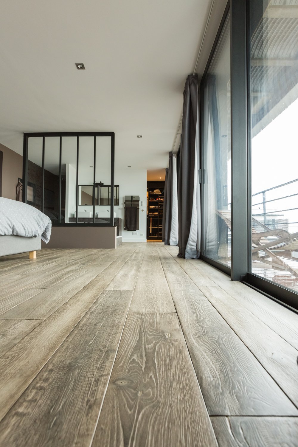 Aged oak floorboards adding texture to a light-filled bedroom interior