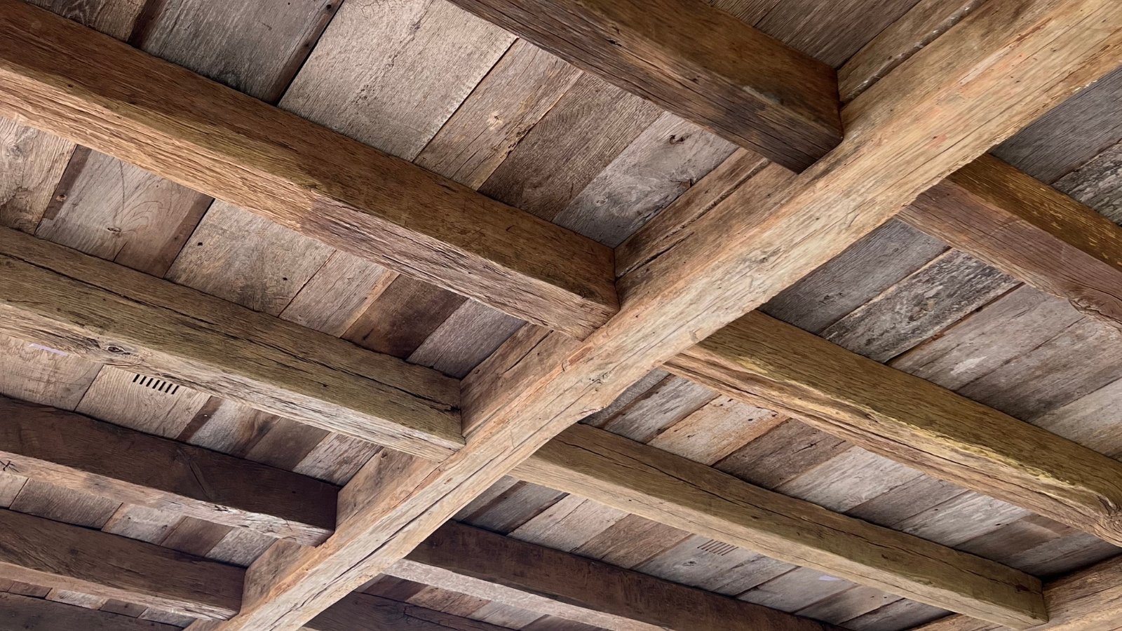 Reclaimed European oak ceiling beams with aged timber lining, natural grain and rustic architectural character.