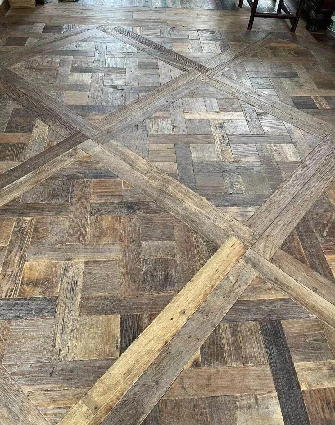 Close-up of a wooden parquet flooring pattern with overlapping wood planks arranged in a decorative design.