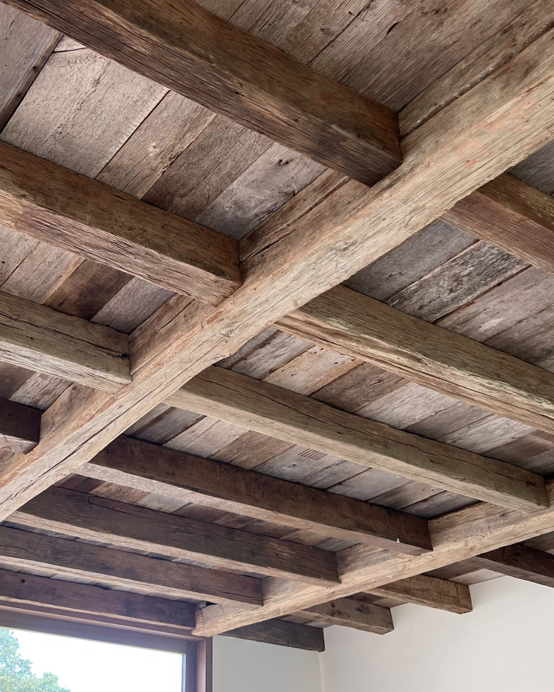 Wooden ceiling with exposed beams and planks, part of a rustic interior design.