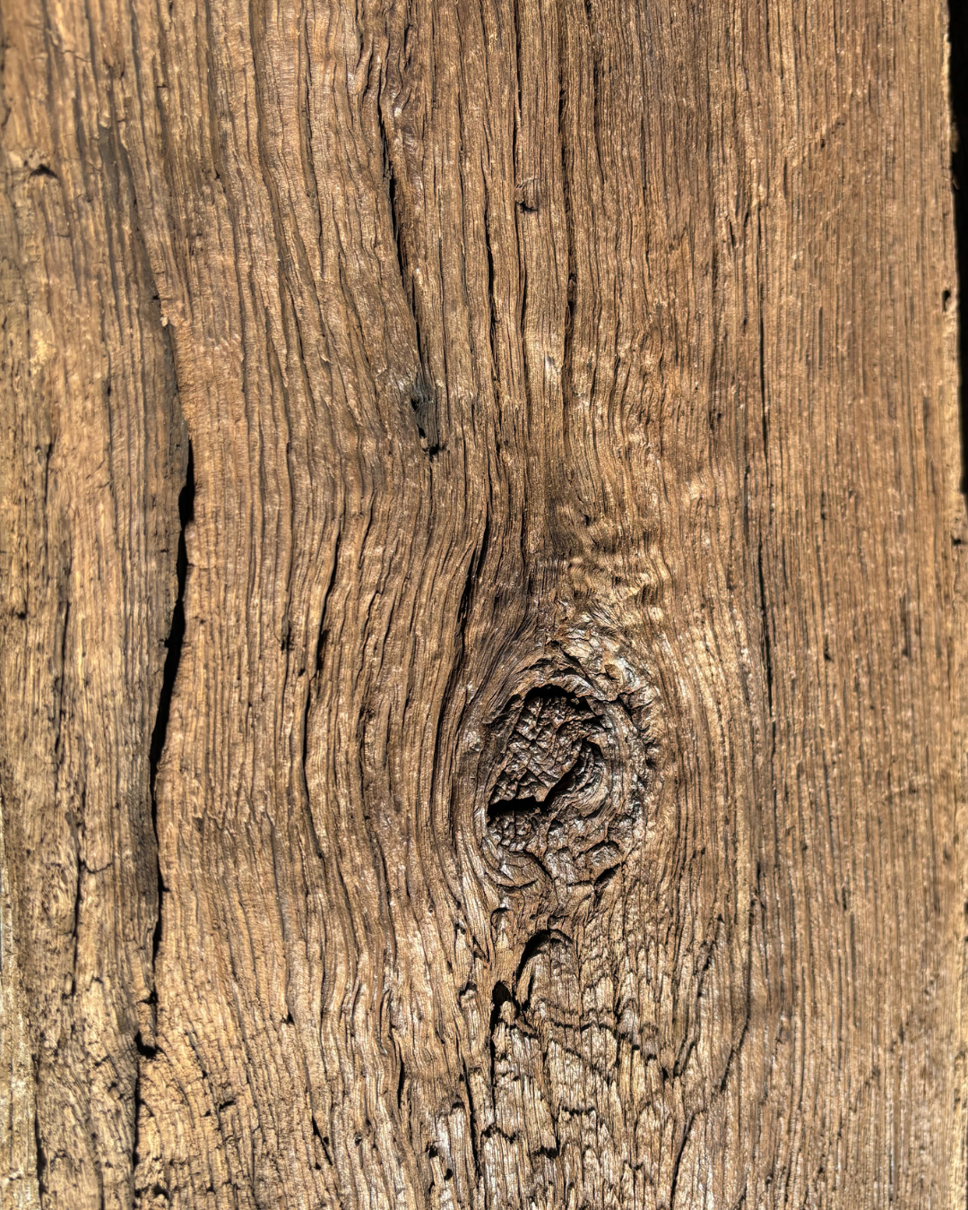 Close-up of rustic reclaimed oak showing aged grain, knots, cracks and natural surface texture.