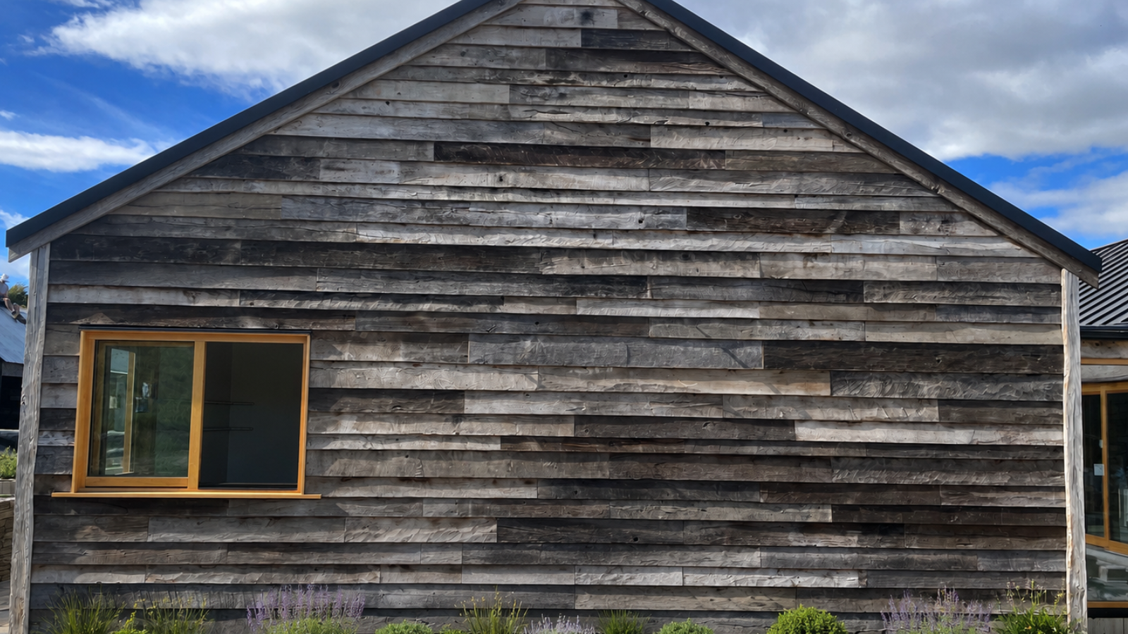 Reclaimed oak exterior cladding installed across a residential gable wall with naturally weathered grey and brown tones.