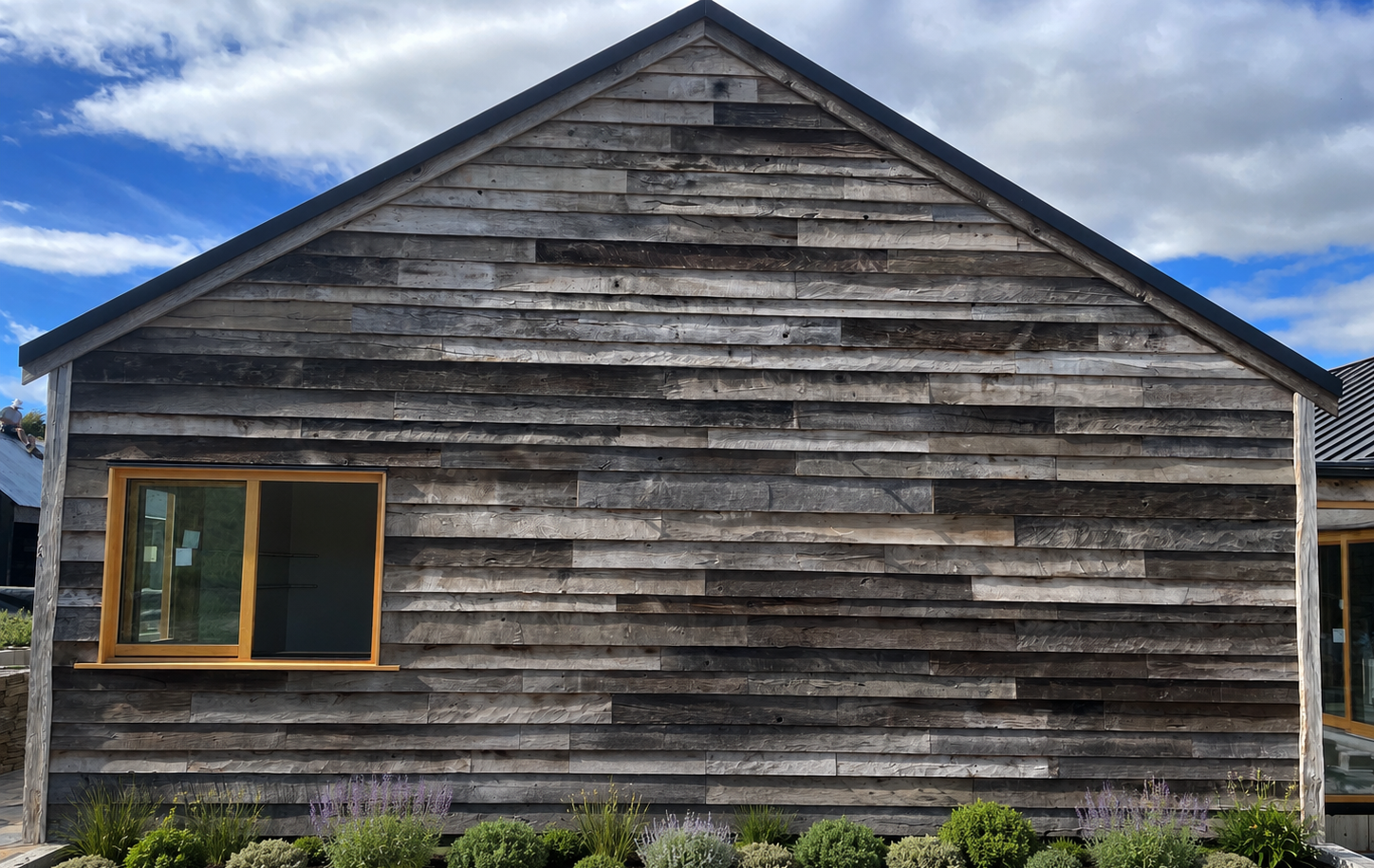 Reclaimed European oak boards used as exterior gable cladding with natural weathering, mixed tones and aged surface character.