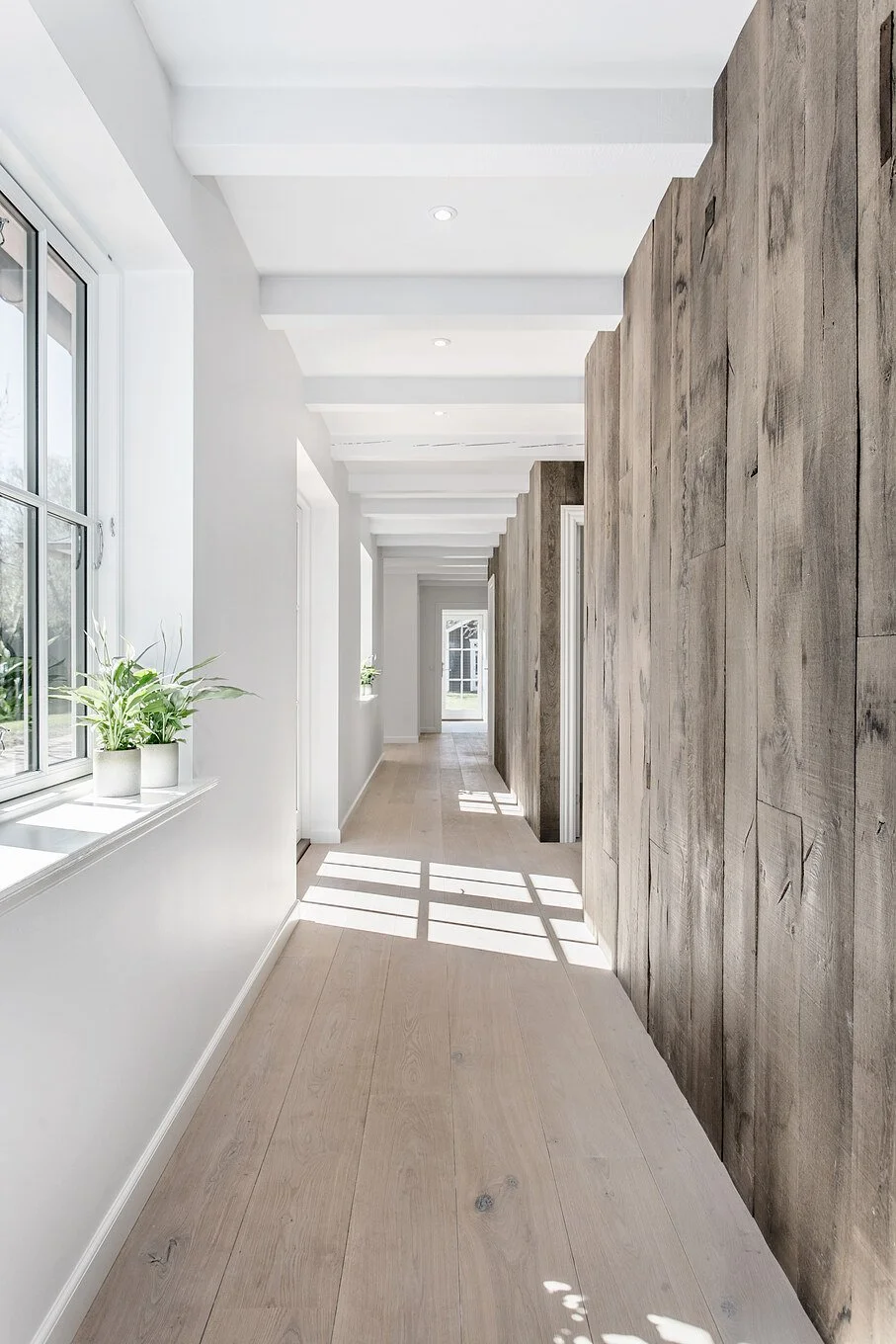 Antique oak flooring in a modern hallway with textured timber feature wall.
