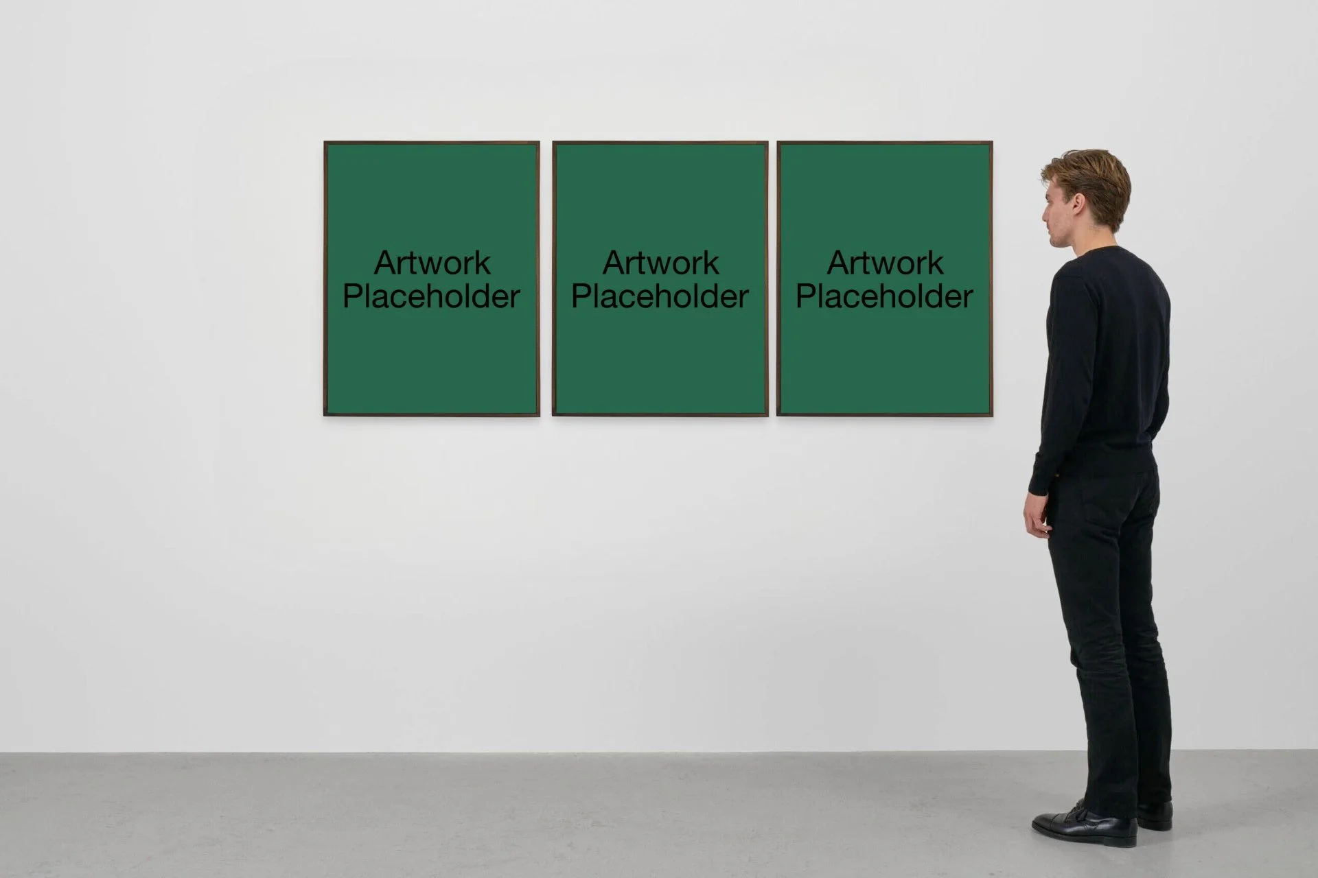 A person standing in front of three empty picture frames on a white wall, each with green placeholder artwork that says 'Artwork Placeholder'.