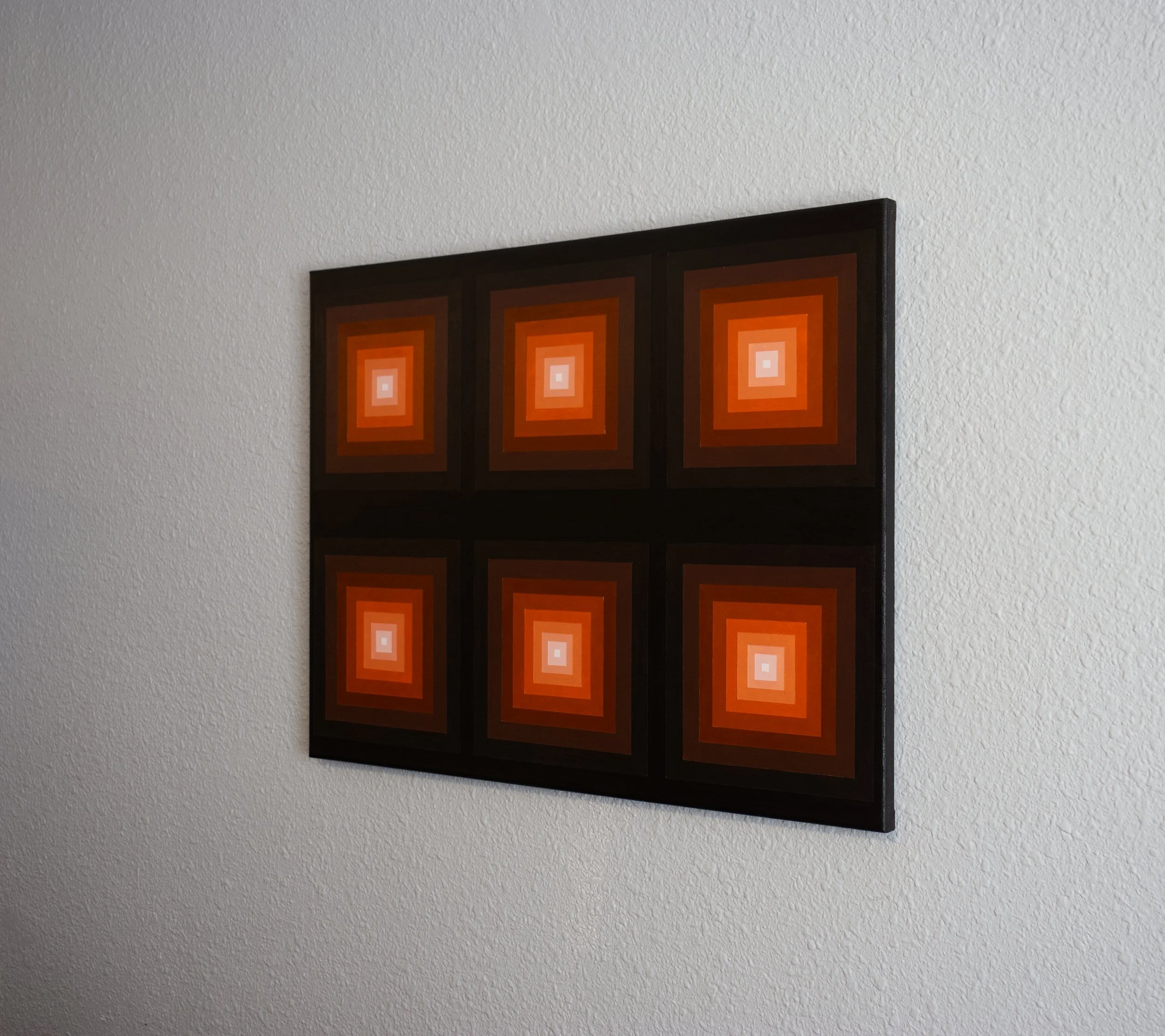 Composition of smaller geometric squares layered to create height, shifting in color from a bright orange center to a dark gradient border.jpg
