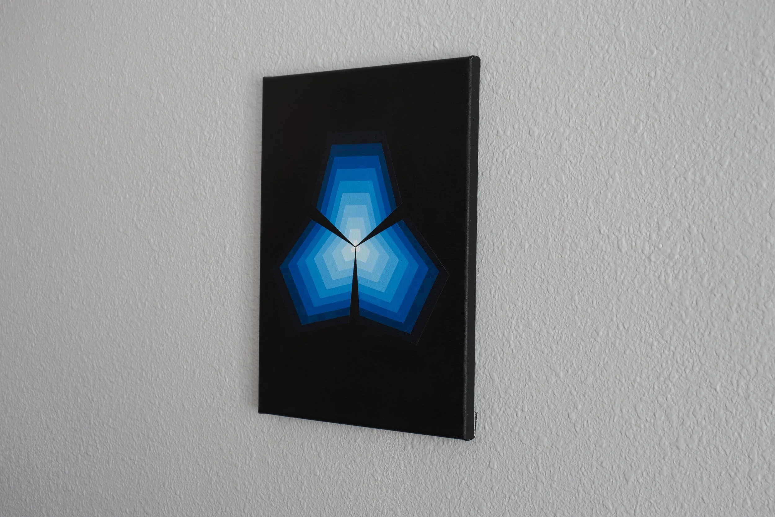 Layered pentagonal shapes on a canvas rendered in a gradient of deep navy blue to bright, luminous azure tints with sharp boundaries.jpg