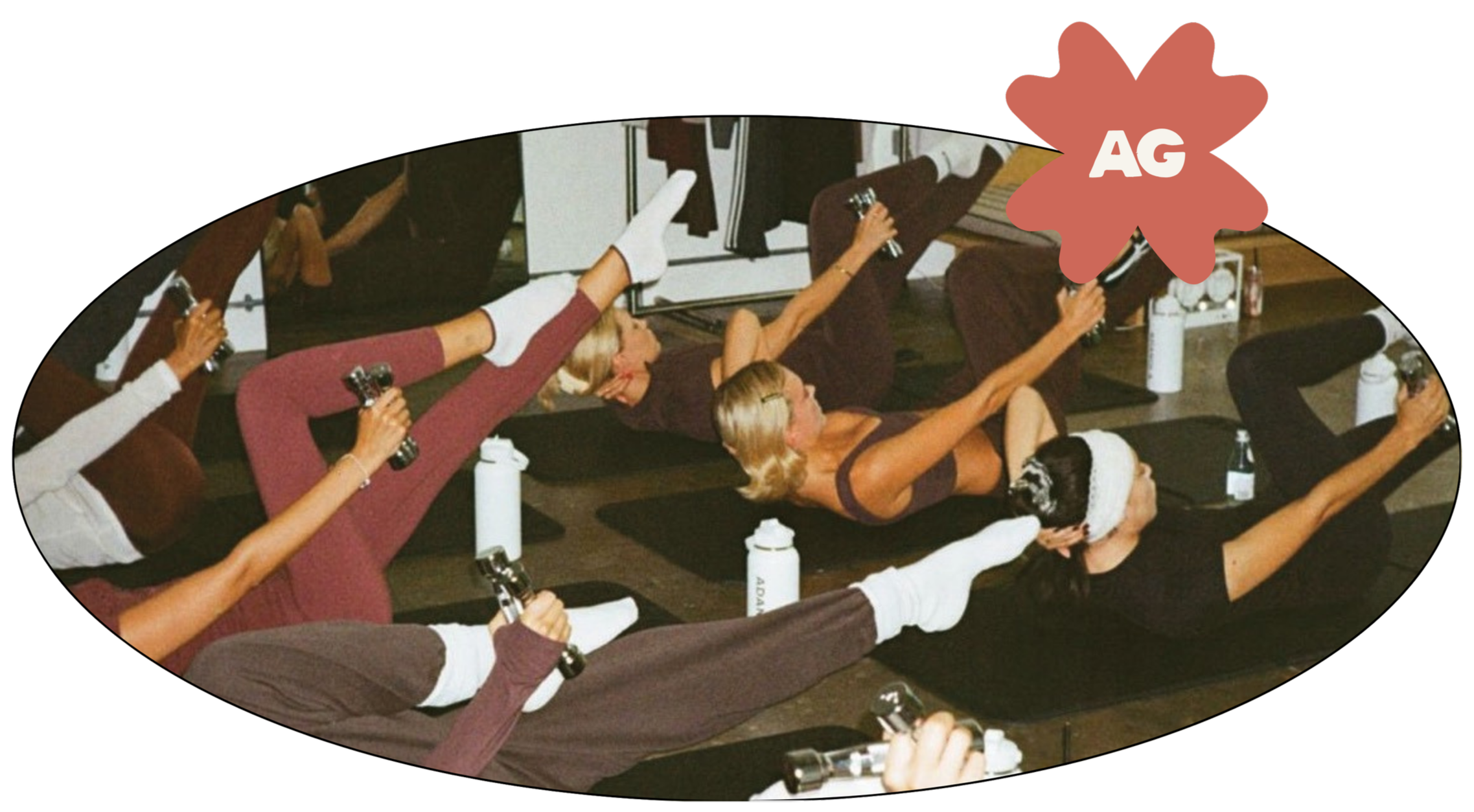 Group of women practicing pilates in a studio, lying on mats, holding small hand weights, with water bottles nearby, wearing comfortable workout clothing.