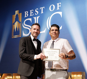 Two men holding a certificate at a Best of SLC awards event.png