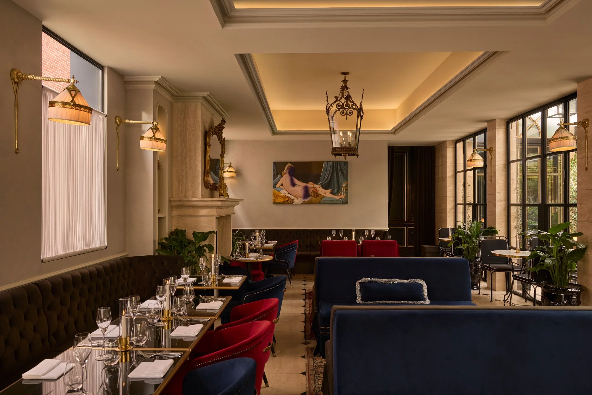 Elegant dining room with large windows, classical light fixtures, and a painting on the wall.