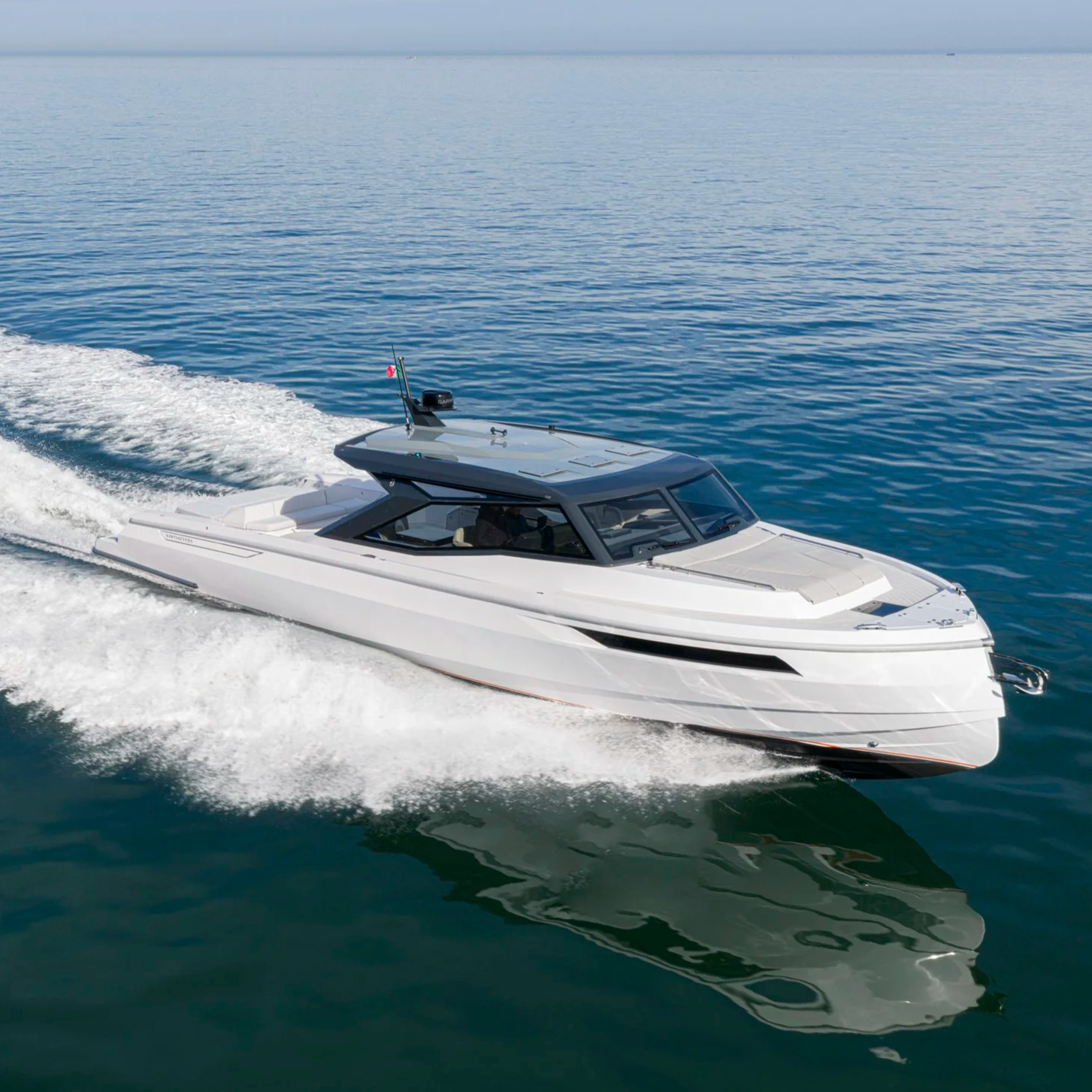 A white yacht cruising on calm blue ocean waters under a clear sky.