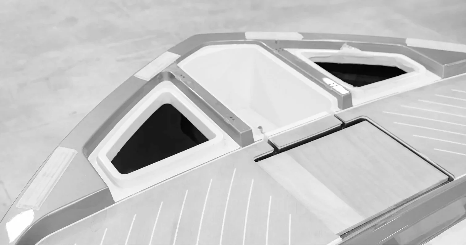 Close-up of the top part of a modern, sleek boat featuring two angular tinted windows and a hatch.