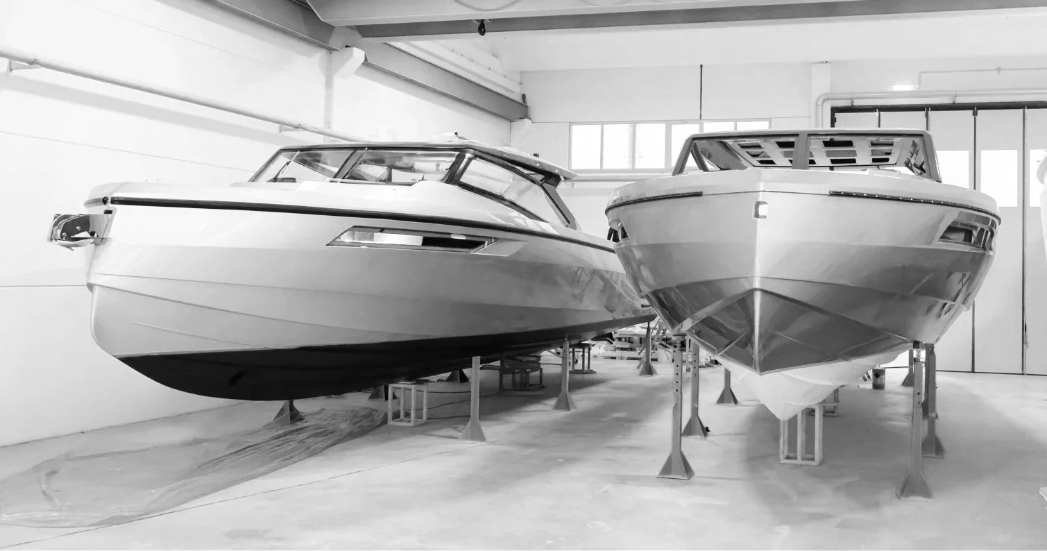 Two boats on stands inside a garage or boat manufacturing facility.