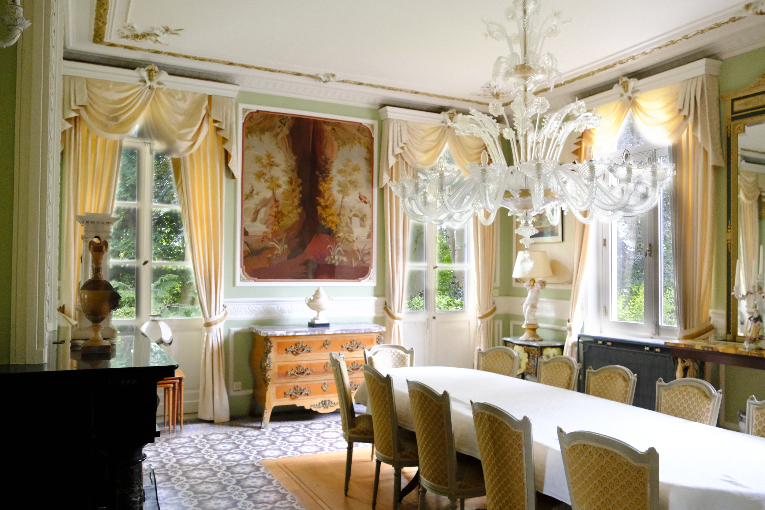 Elegante woonkamer met grote ramen, kroonluchter, schilderij, antique meubels en chique gordijnen. | Kasteeldomein Battenbroek