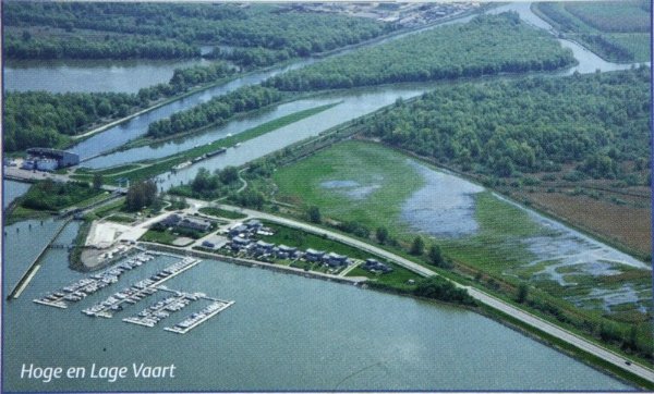 Aerial view of a marina with boat slips, surrounded by green fields, wetlands, and water channels in a rural landscape.