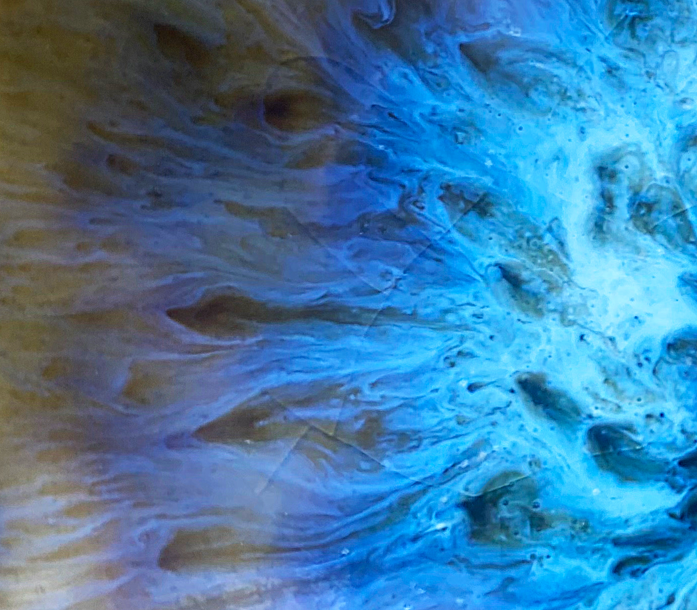 Close-up of textured, swirling water with blue and beige hues.