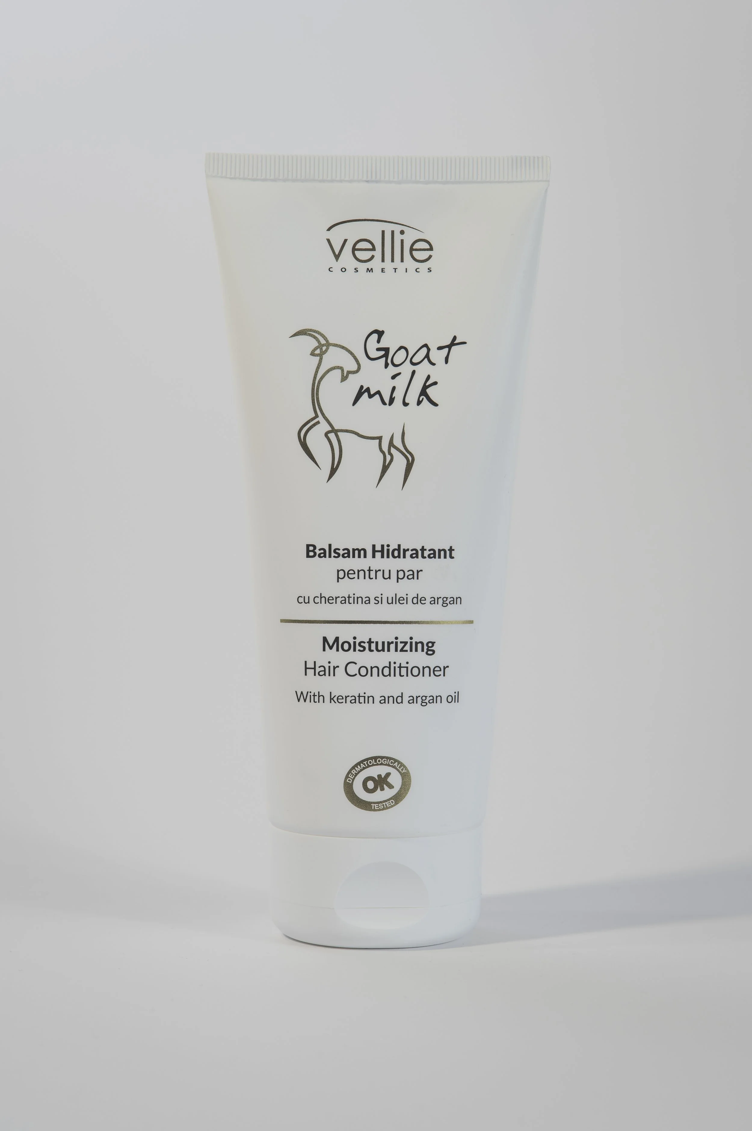 A white tube of goat milk hair care product with a cap, labeled 'Vellie Cosmetics', with a goat illustration and text in French and English. The product is a moisturizing hair conditioner containing keratin and argan oil, tested dermatologically.