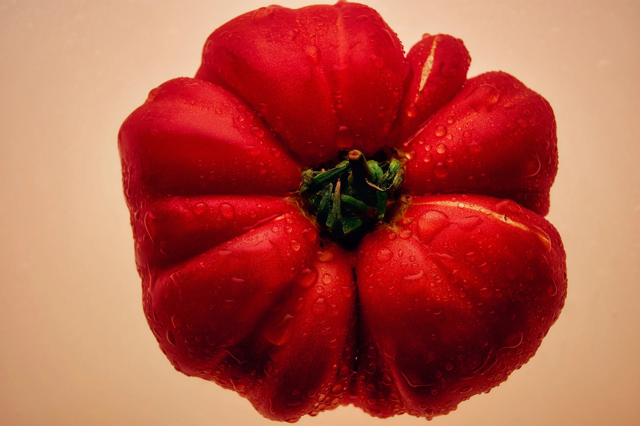 A close-up image of a red bell pepper with water droplets on its surface.