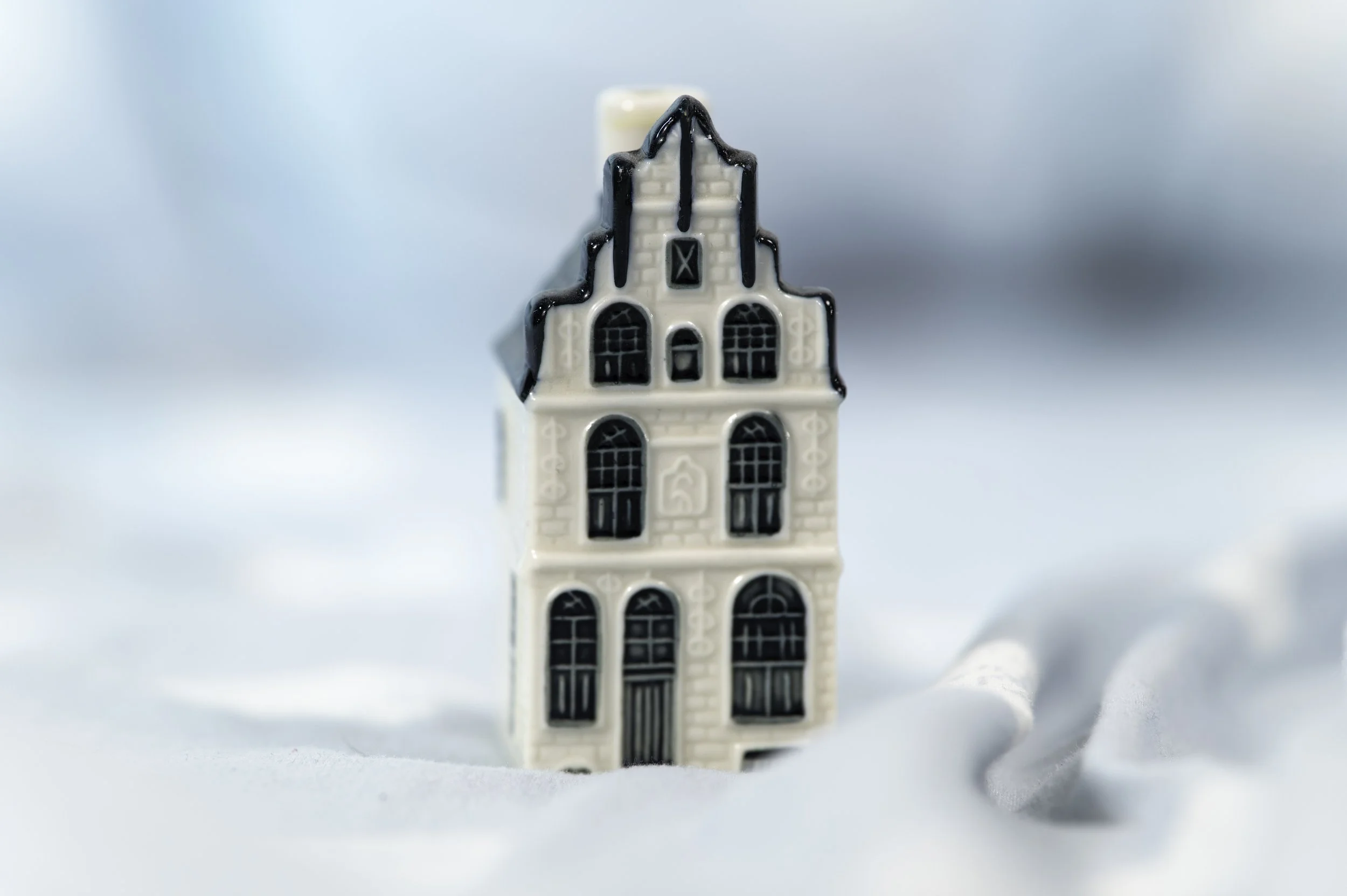 Close-up of a small white ceramic building with black detailing, resembling a castle or church, placed on a light surface with a soft background.