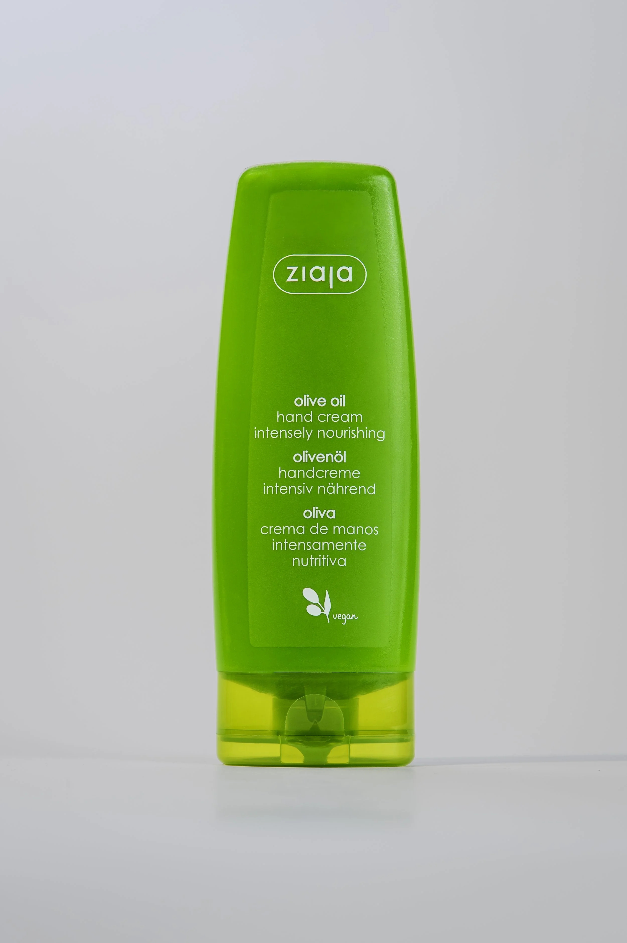 Green bottle of Ziaja olive oil hand cream with white text and vegan symbol on a white background.