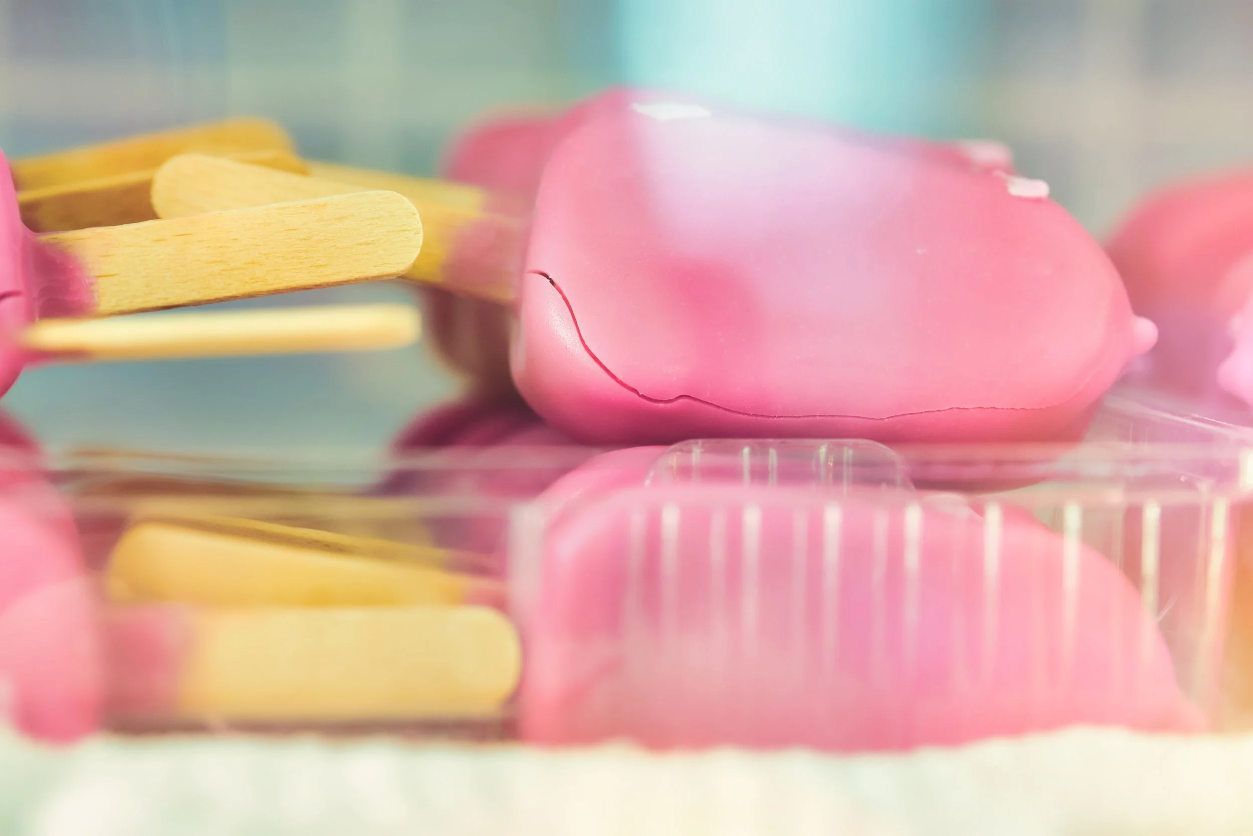 Close-up of pink and yellow ice cream popsicles in a display case.