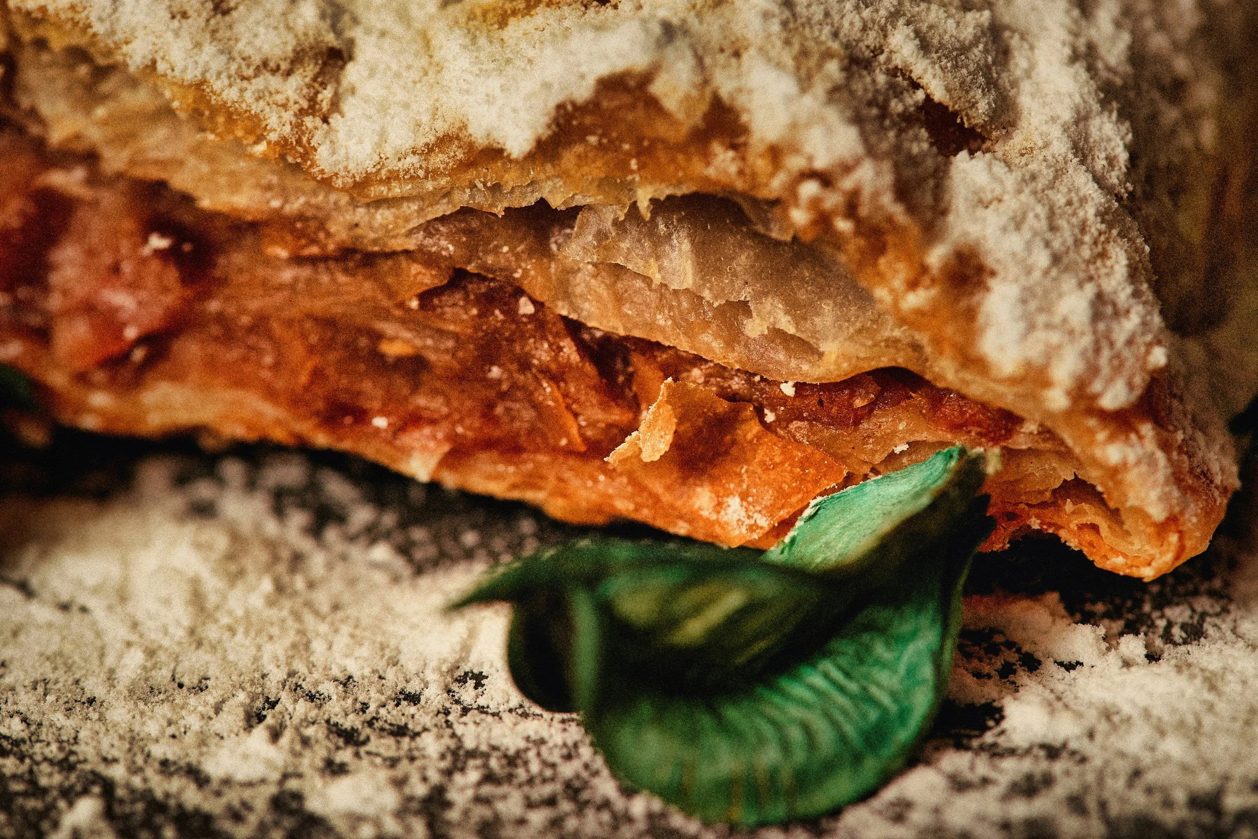 Close-up of a baked meatloaf with a crispy top, garnished with fresh green herbs.