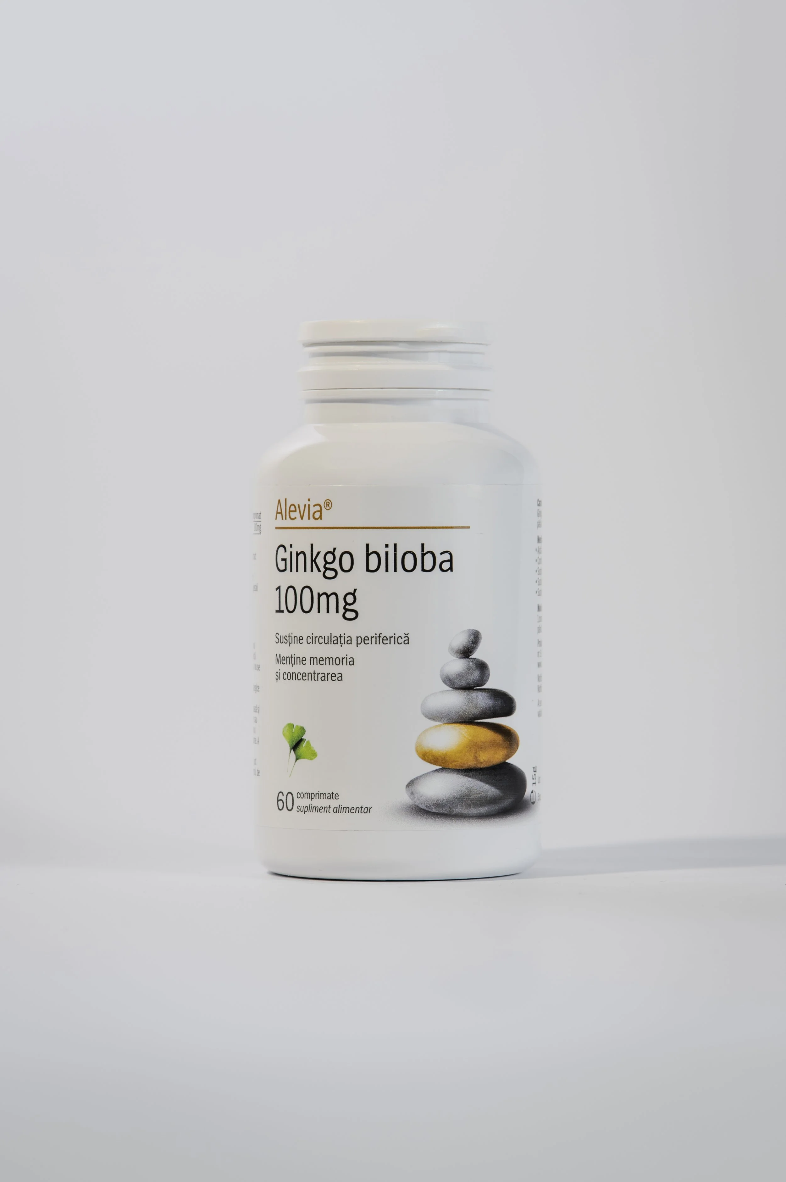 A white bottle of herbal supplement with a label that reads 'Ginkgo biloba 100mg' and features an image of stacked stones and green ginkgo leaves.