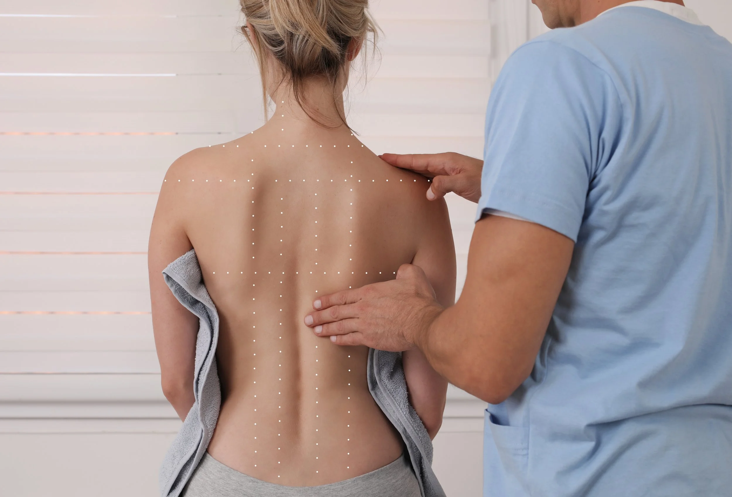 Un nostro medico esamina la schiena di una paziente per individuare la causa di dolori o limitazioni fisiche e creare un programma di riabilitazione personalizzato