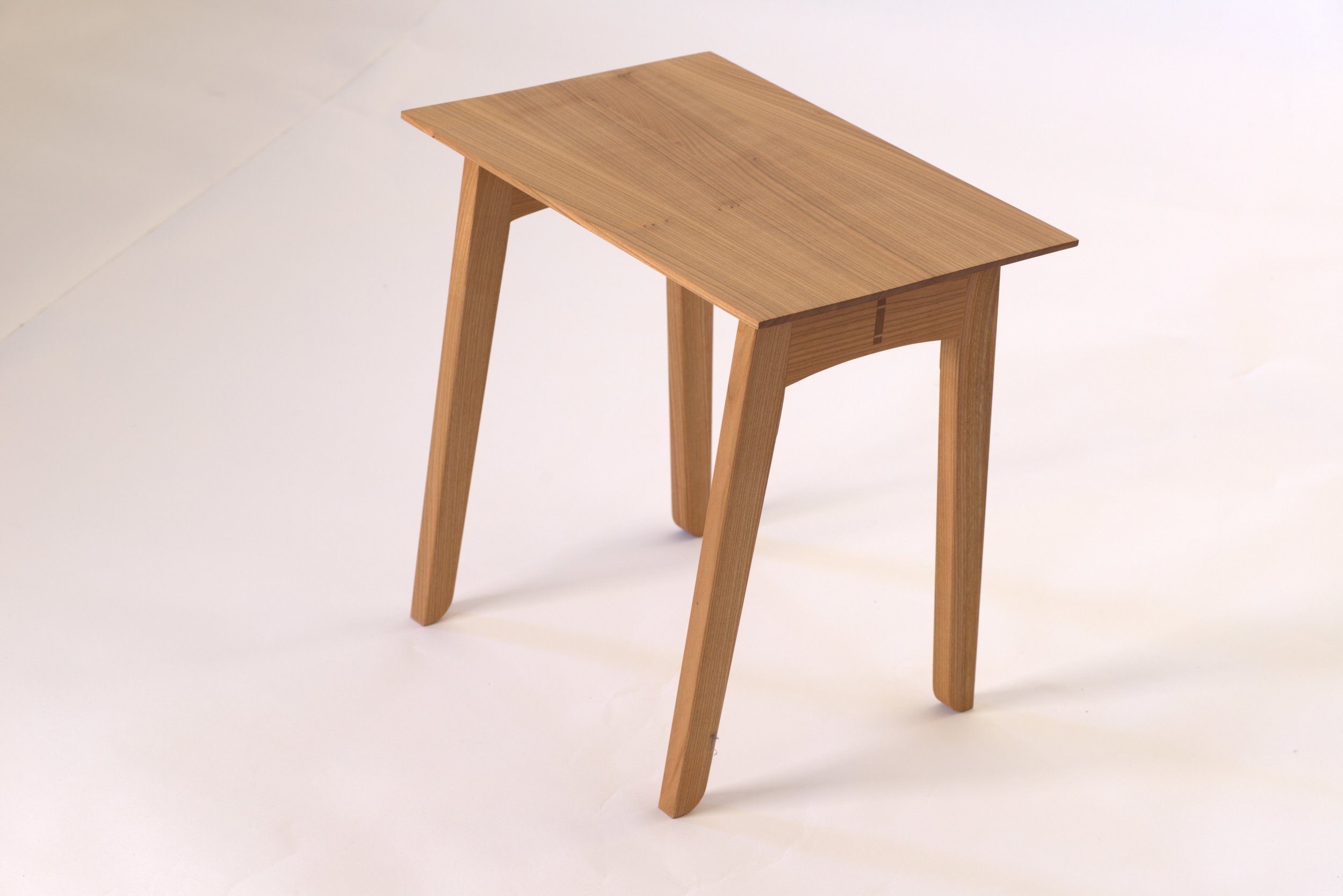 A wooden table with four legs placed on a plain white surface.