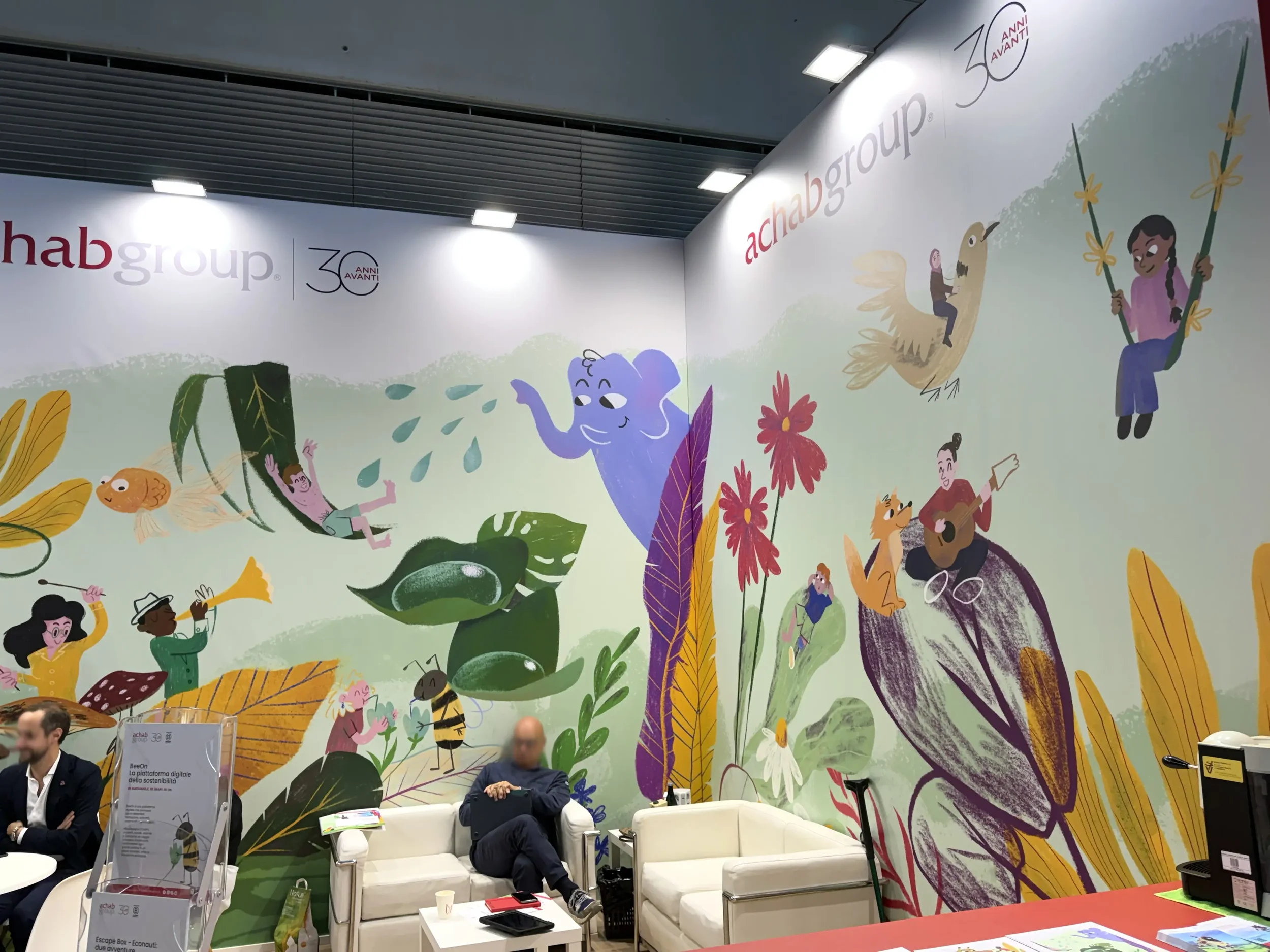 Foto dello stand Achab Group a Ecomondo 2025 con l'illustrazione murale del giardino surreale applicata sulle pareti